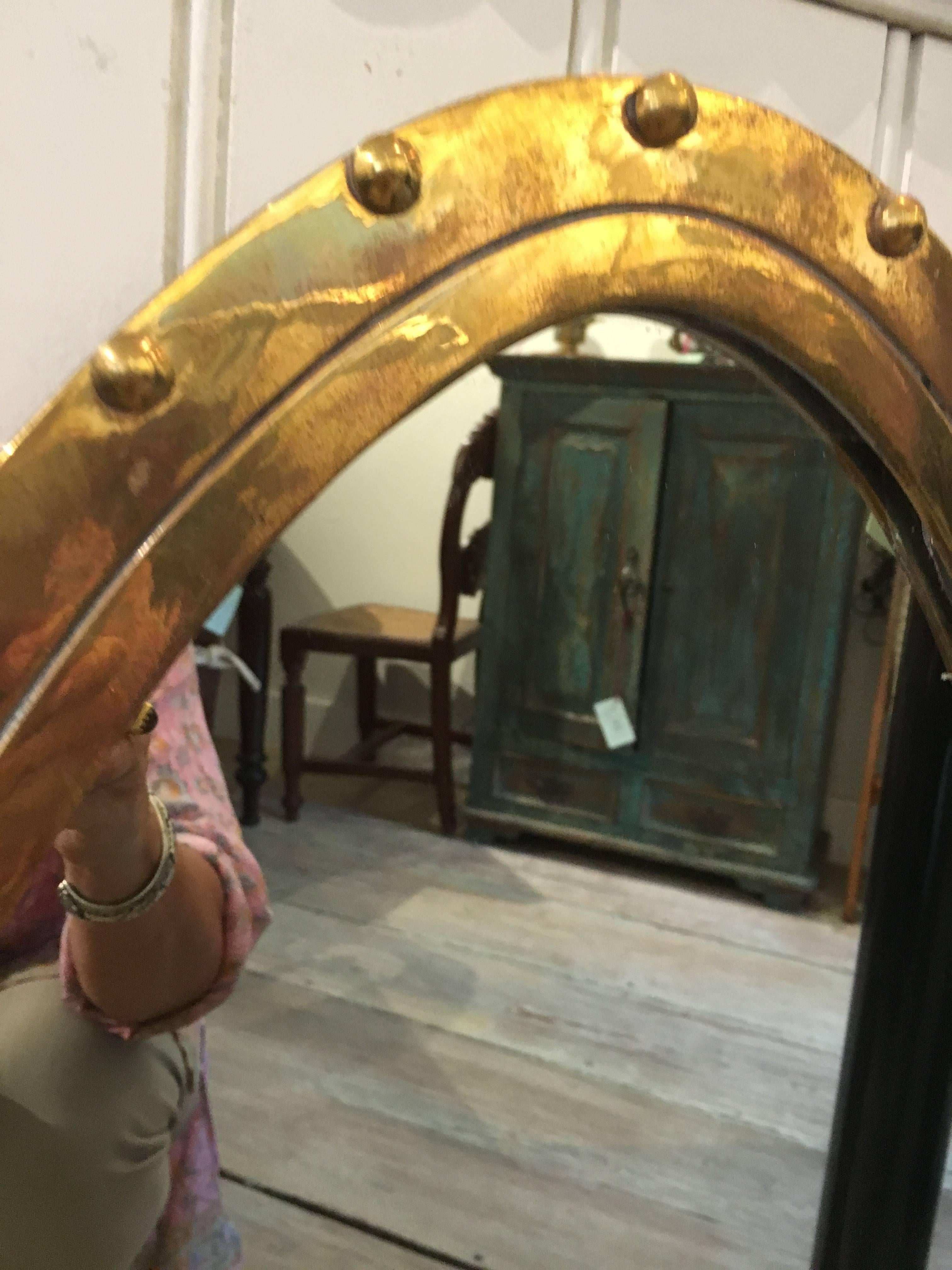 A great ovoid-shaped brass ship's window turned into a mirror. Originally salvaged from a ship's closed-type lifeboat from the 1970s. The glass has been swapped for a mirror and the rivets have been put back in. Brackets added to the back along with