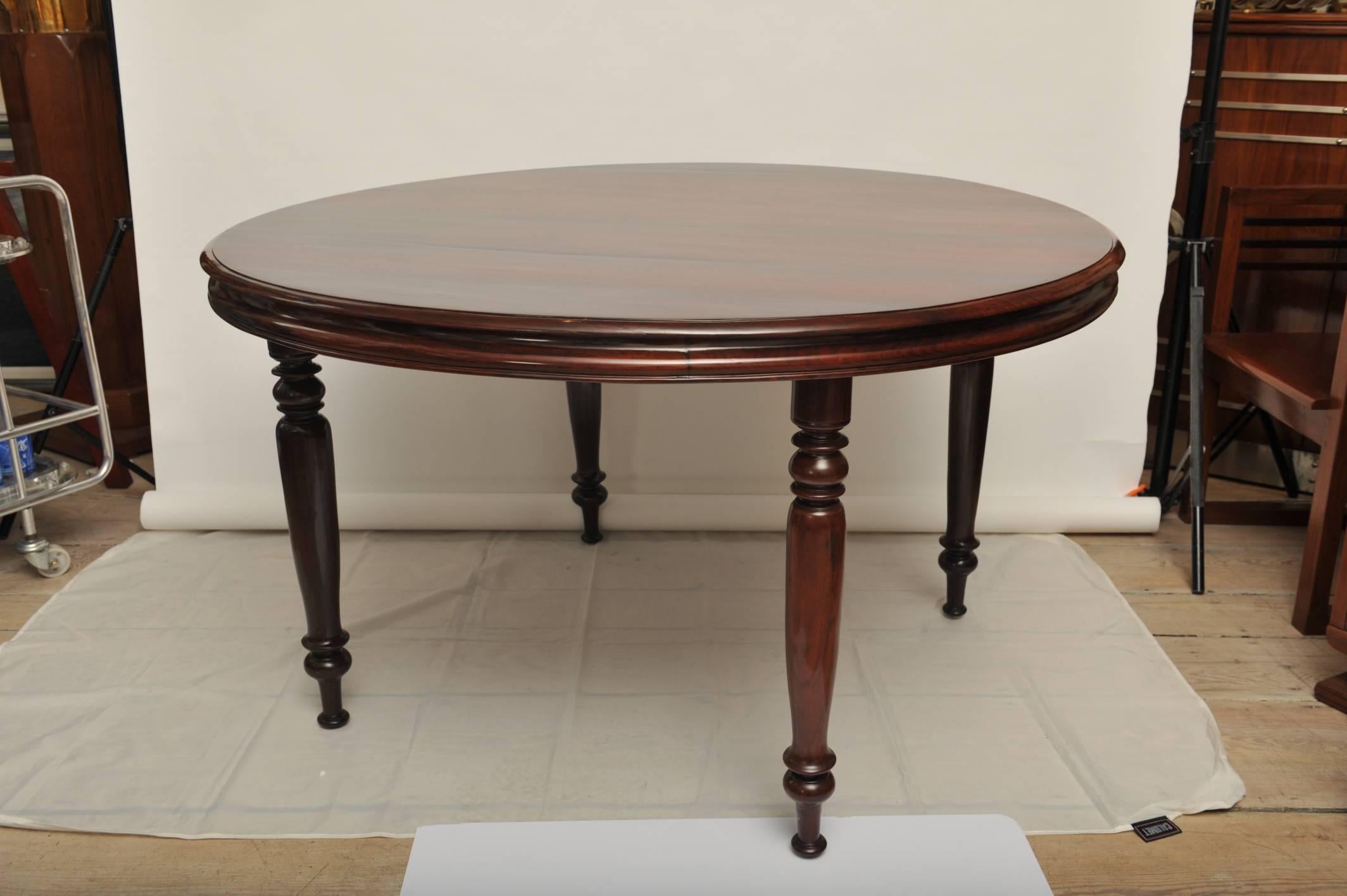 Elegant and rare British Campaign solid wood dining table. Reeded edges and turned legs, which unscrew from underneath the tabletop for easier transport-- typical of the Campaign pieces, designed to store and travel. Refinished.  Round dining tables