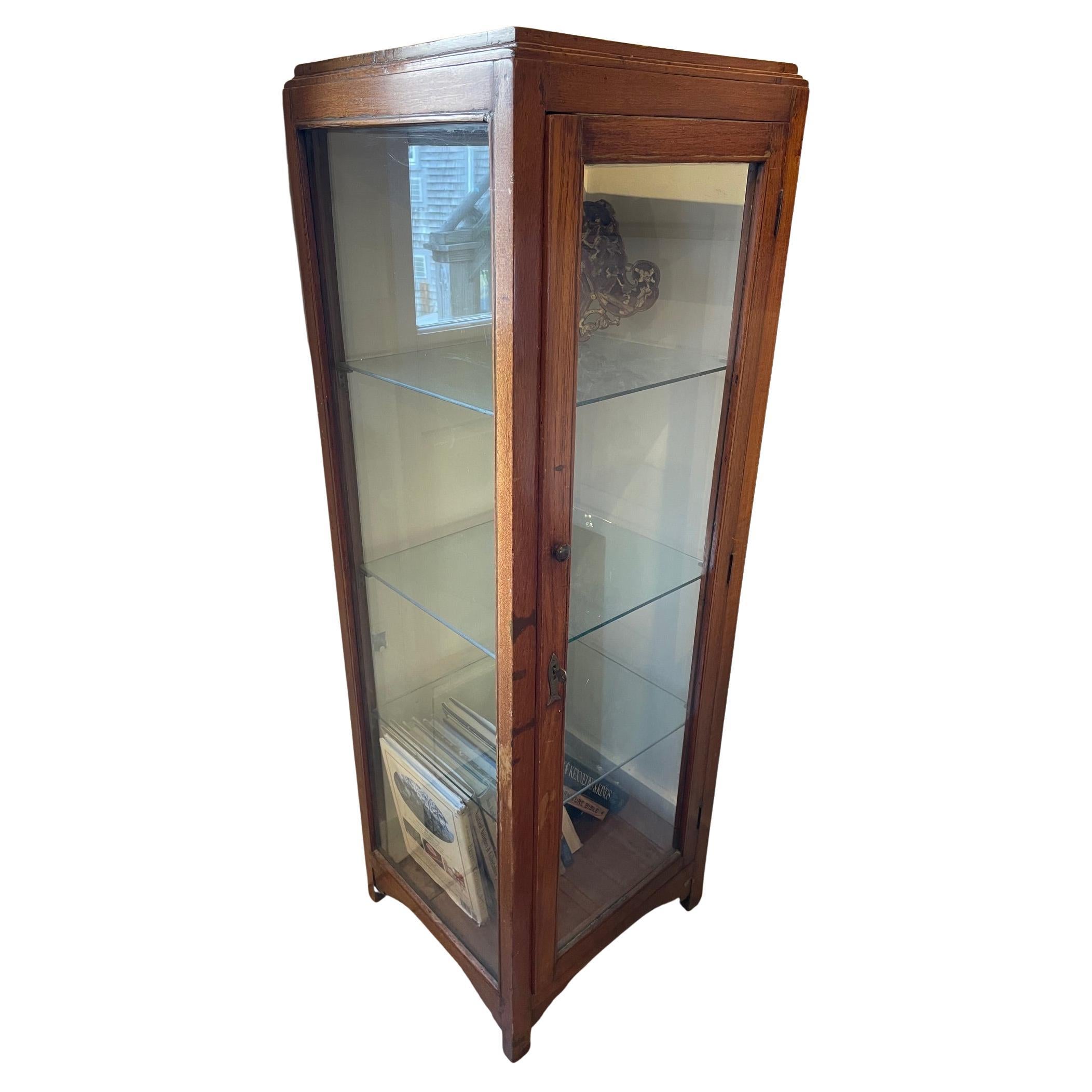 Vitrine en teck et verre avec étagères intérieures en verre.  L'écusson de la serrure est orné d'un poisson en laiton.  Les mesures verticales des étagères intérieures, de haut en bas, sont de 13