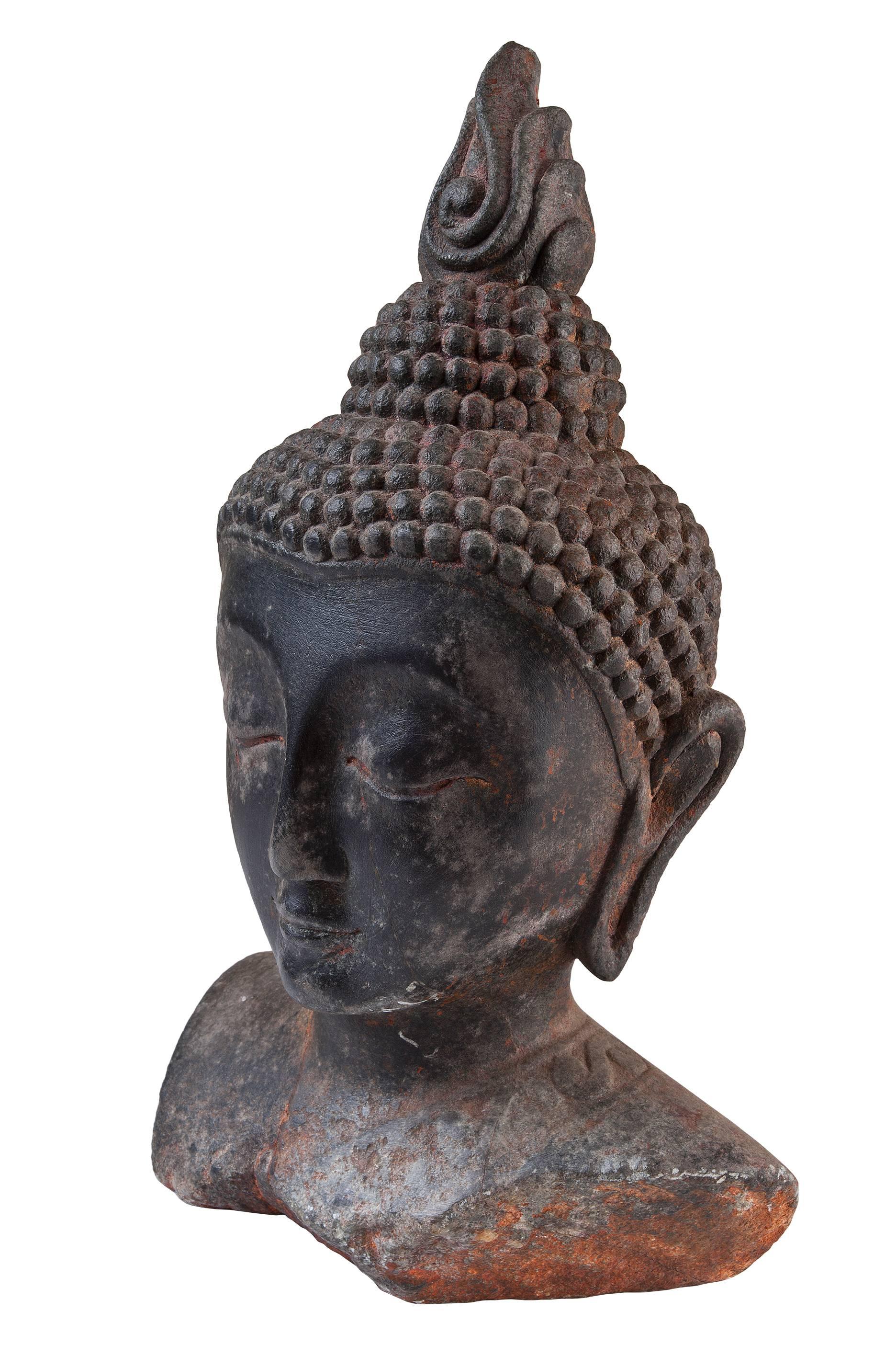 A beautiful Thai Buddha head made of stone with excellent patina dating from the early 1900's. Features include the typical curled hair, elongated ears and half-closed eyes. The ushnisha crown with flame depicts the wisdom and illumination after
