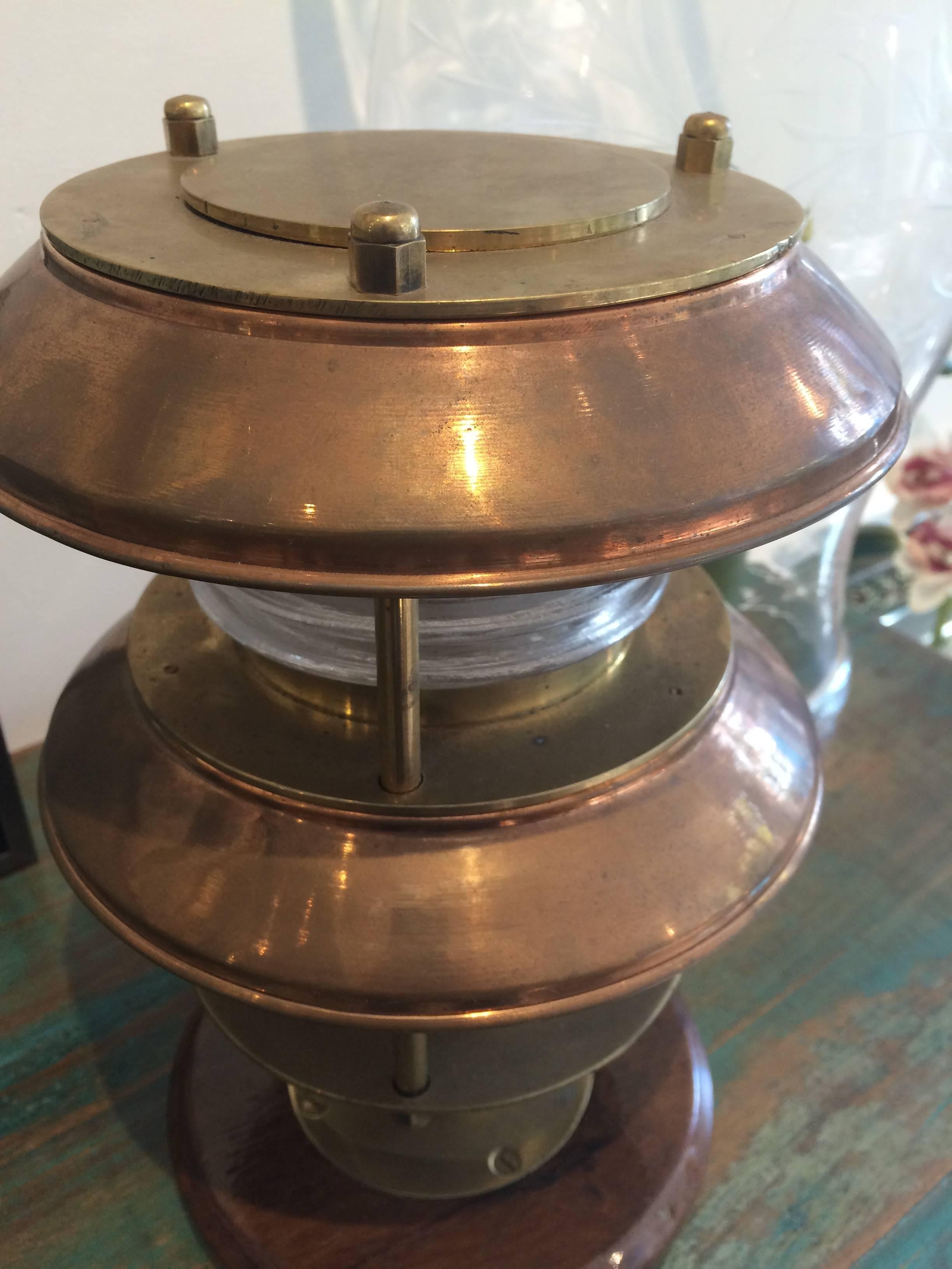 Pair of ship's post lights, copper and brass with fresnel lens. The teak base has been added. It takes a regular size bulb and has been rewired for American use. Mid-Century.

Nautical antiques located on Nantucket Island.