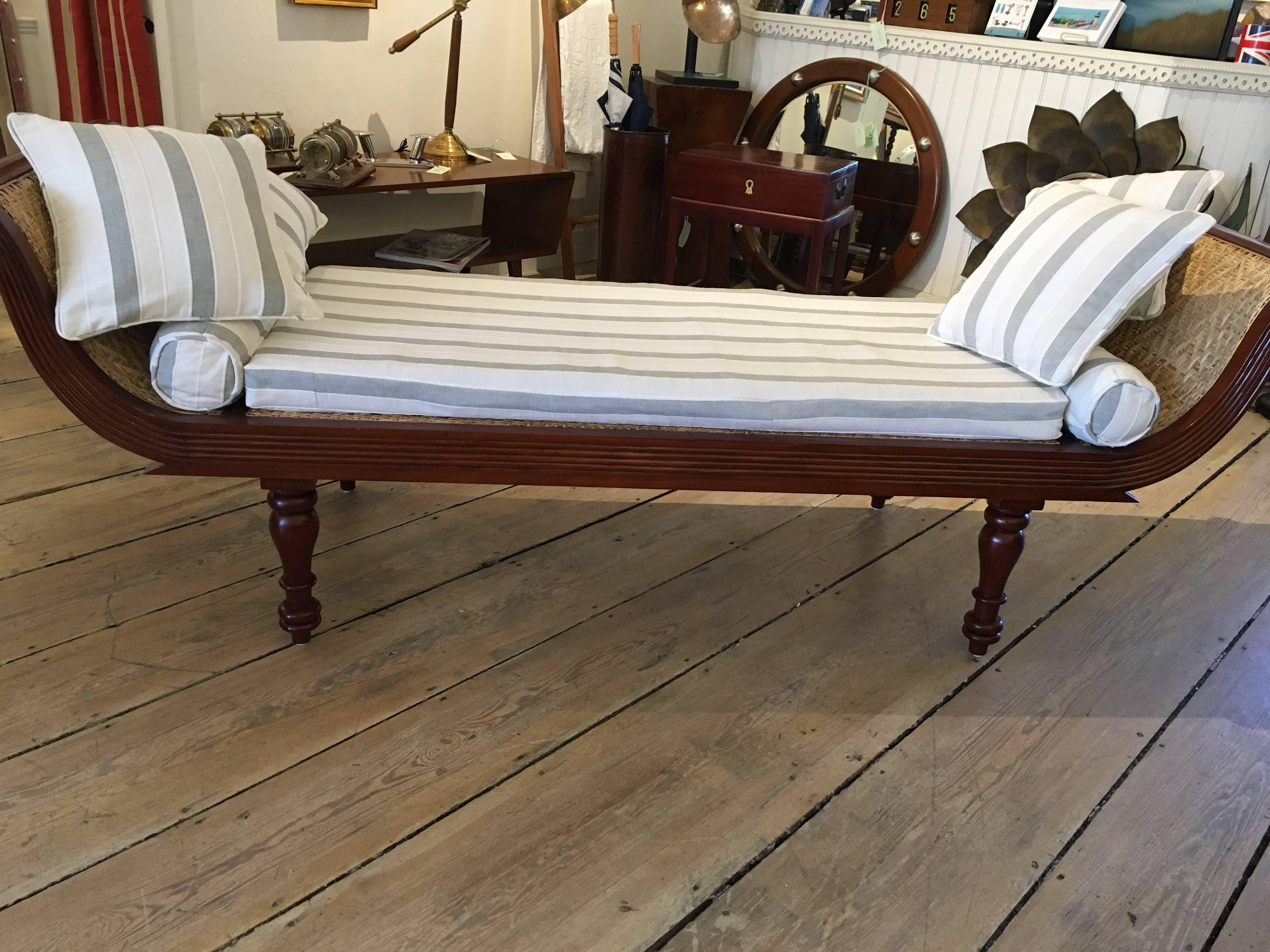 A lovely teak double sided daybed with a caned seat (redone with a very tight, sturdy weave). Features turned legs and carved, reeded fronts on both sides. It has a custom-made cushion with a white and grey stripe and zippers off when needed, circa