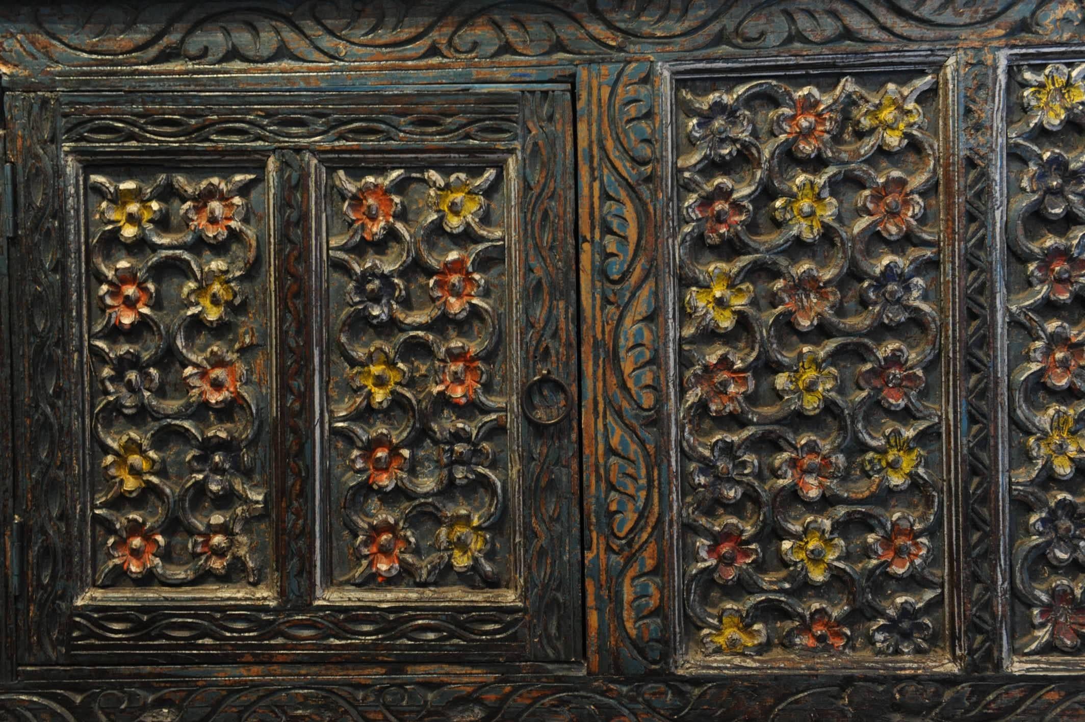 Intricately carved Indian teak sideboard with floral and vine motif and original paint. Centre opening with three lower drawers, late 19th century, Gujarat, India.