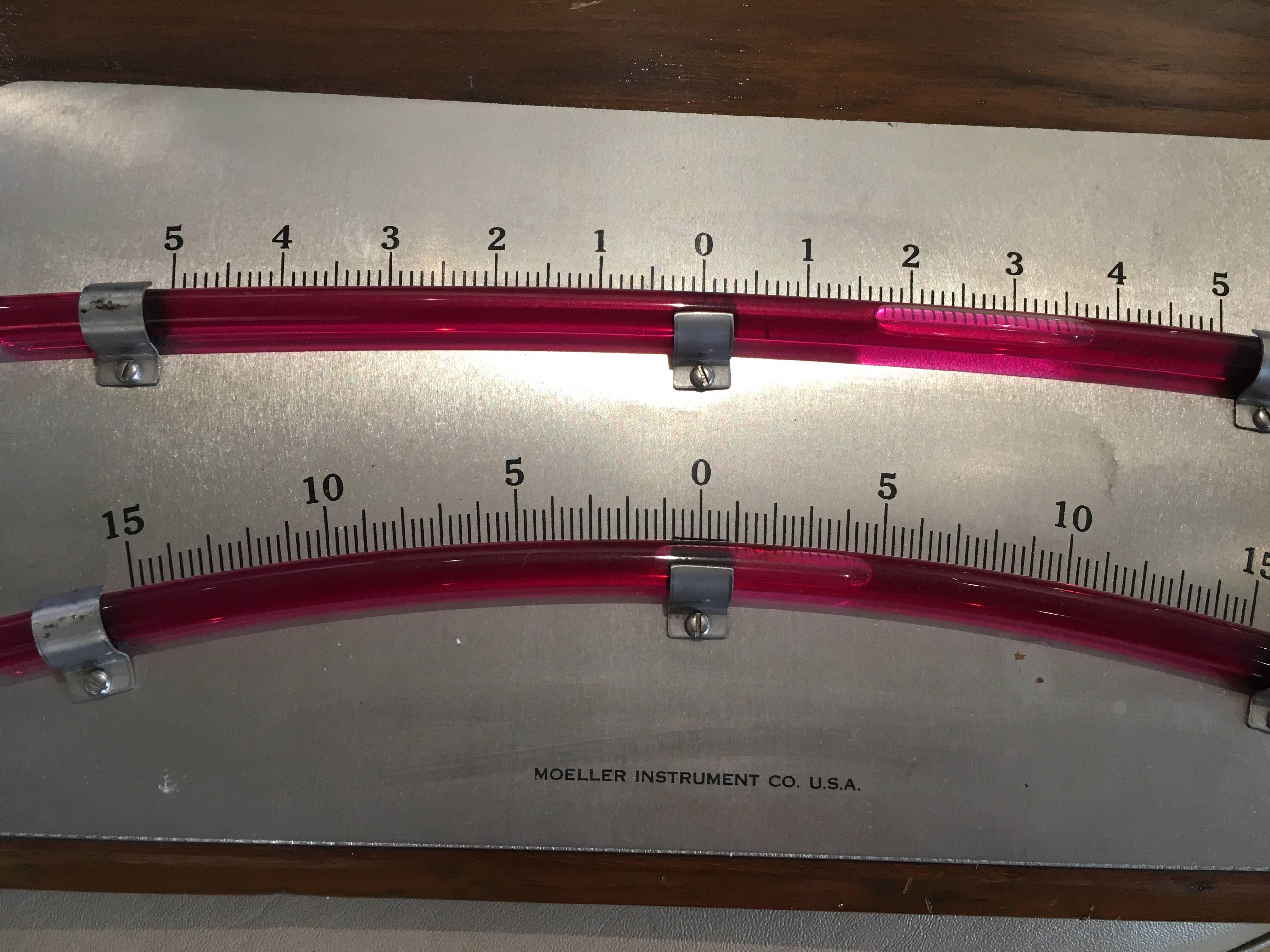 A double gauge bubble clinometer with precision glass tubing and nickel face mounted on a teak back plate. These tilt gauges were used on vessels to measure the angular slant of the ship. The readings are important when heeling underway, and also