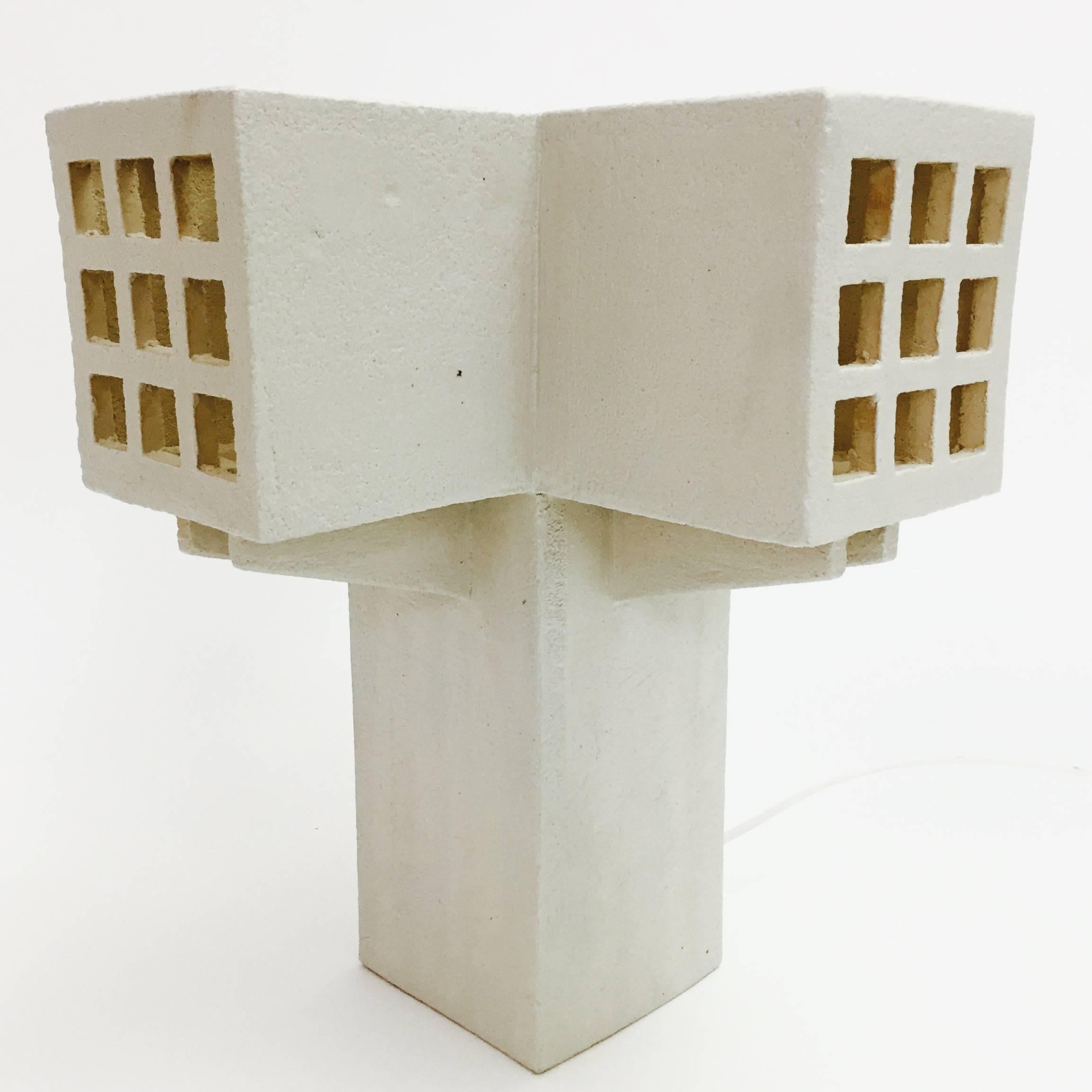 Geometric sculpture, forming a cross table lamp, textured clay glazed in shades of pale cream, decorated with open windows perforations.
One of a kind contemporary handmade creation, designed by the French ceramicist.

Note to International