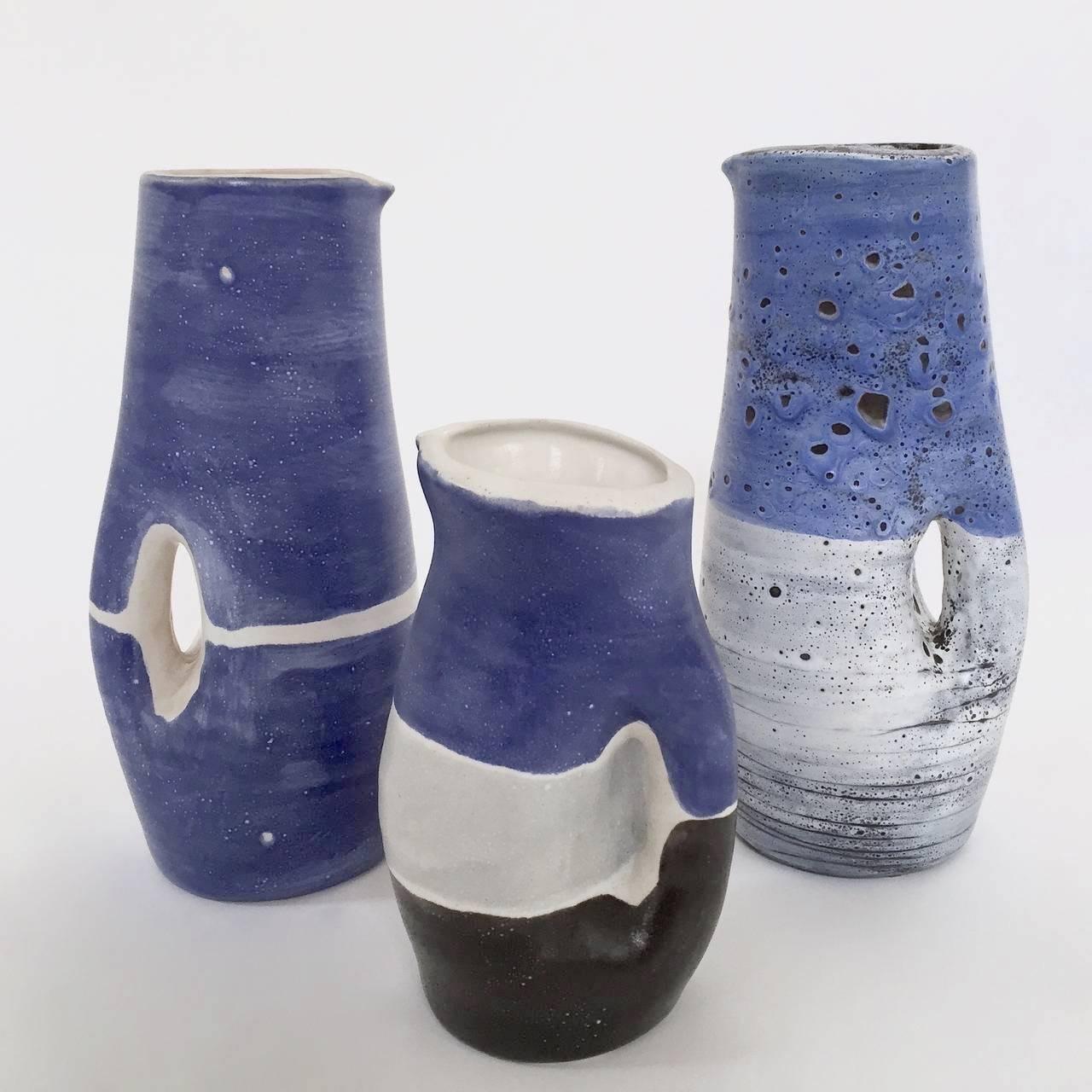 A rare set of 3 earthenware organic shaped pitchers glazed in shades of cloudy and deep blue, grey and white. 

Two of the three pieces are signed M.J on the bottom.
France, circa 1955-60

The dimensions approx. are : 
Largest pieces : H 32 cm
