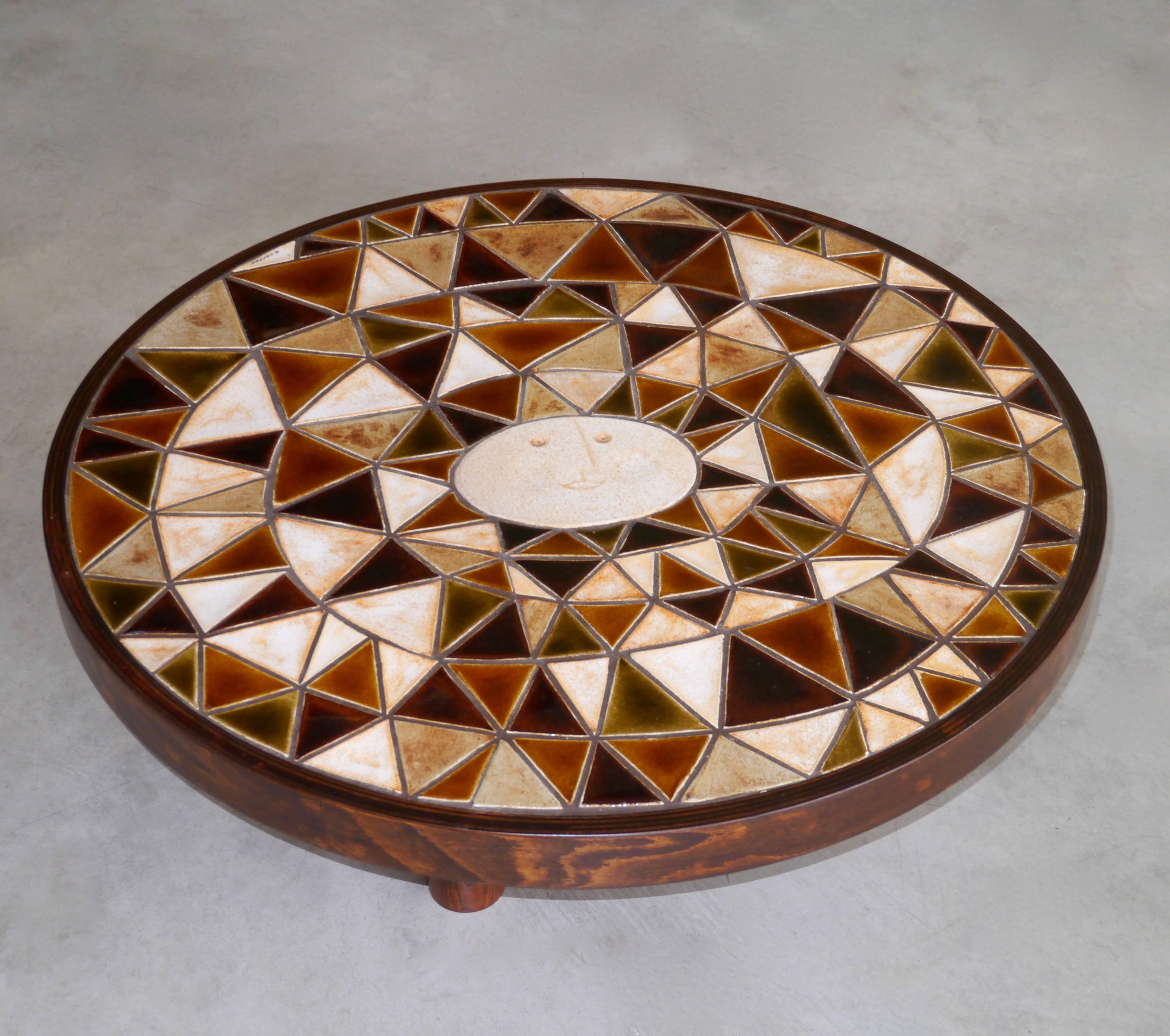 The table top consists in triangular stoneware parts in various shades of matte and shiny glazes and forming a sun which is probably the most iconic subject of Capron's achievements.

Wooden belt and feet.

Signed Roger Capron on tile.
 