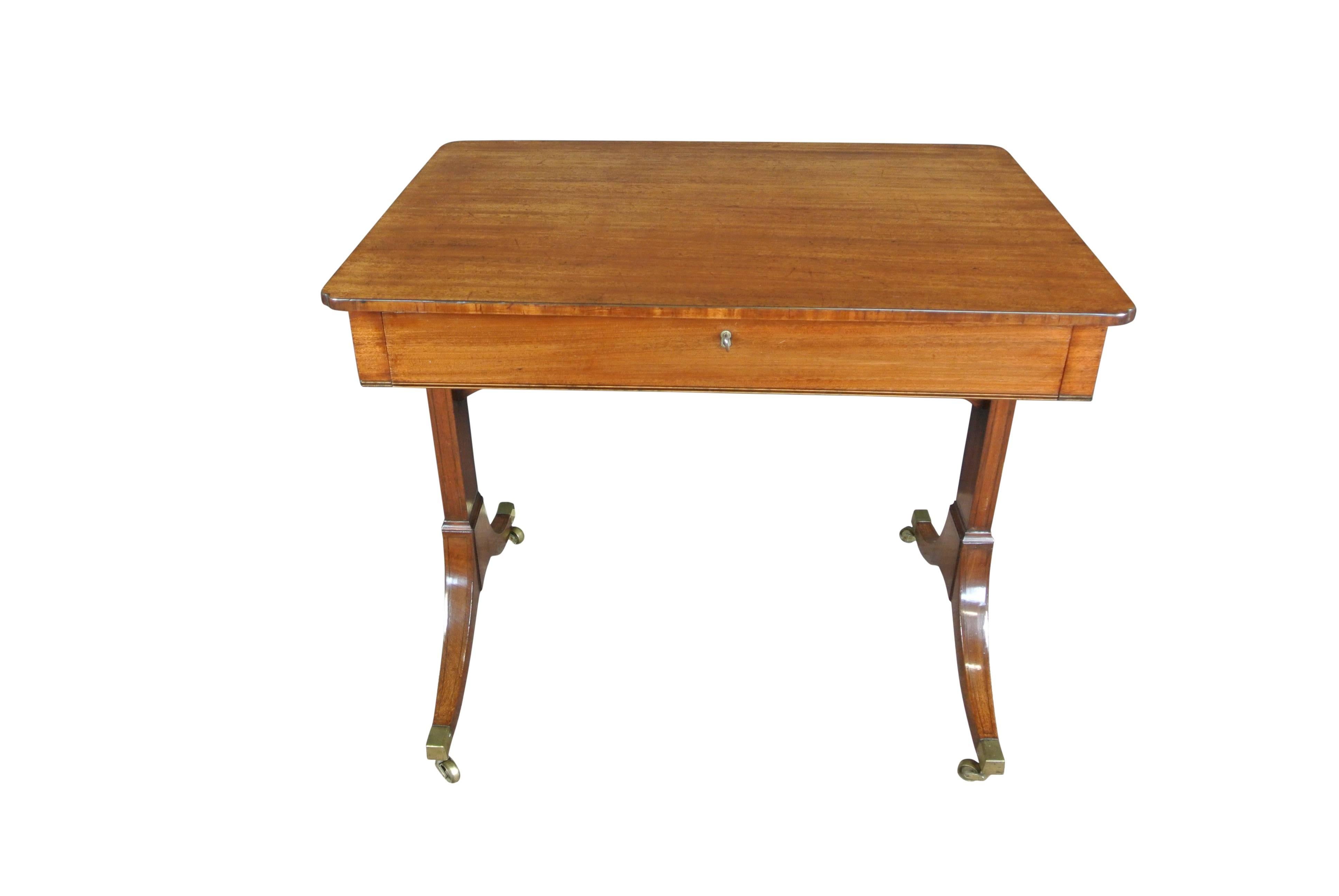 A fine Regency mahogany and inlaid ebony single drawer occasional table with Re-entrant corners and end supports on outswept feet ending in brass castors.