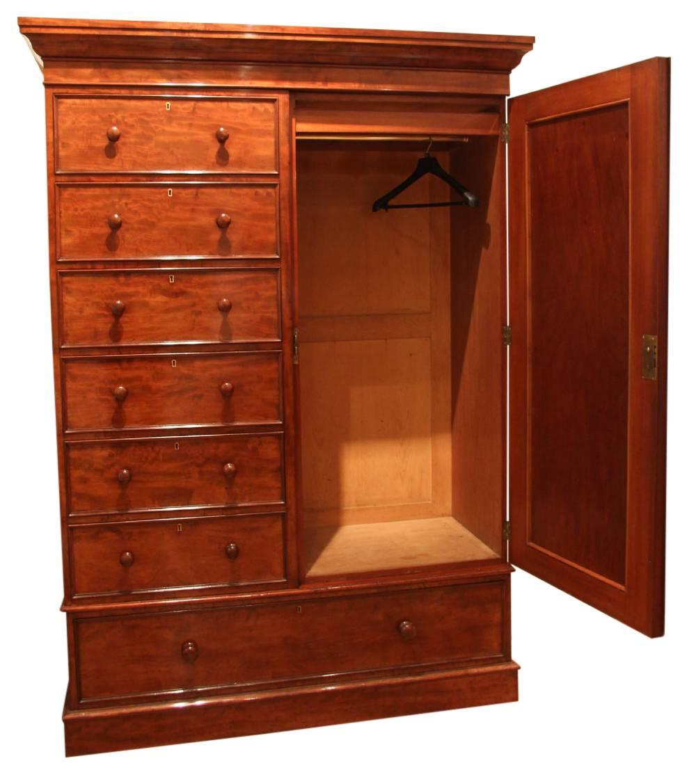 A superior quality mahogany compactum wardrobe consisting of six short reverse graduating drawers over one long adjacent to a hanging wardrobe.