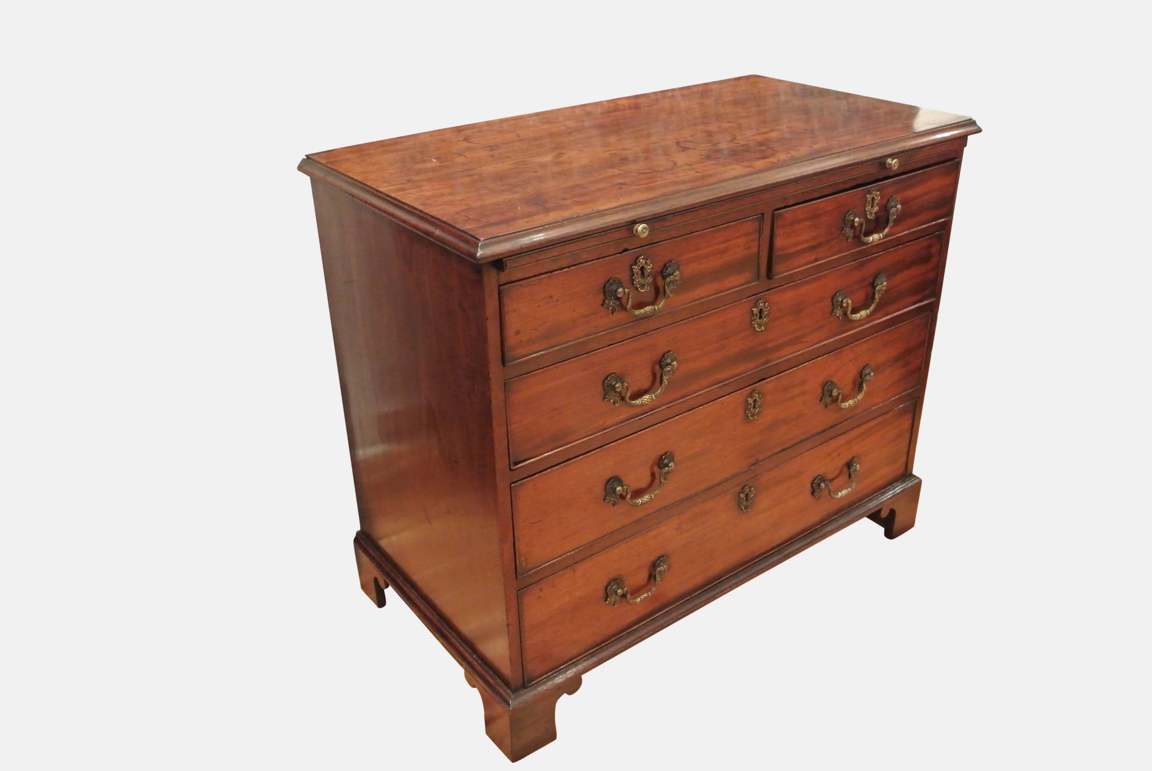 A handsome and well patinated George III oak lined mahogany chest of drawers with brushing slide and two short, three long drawers with original brassware, standing on bracket feet.