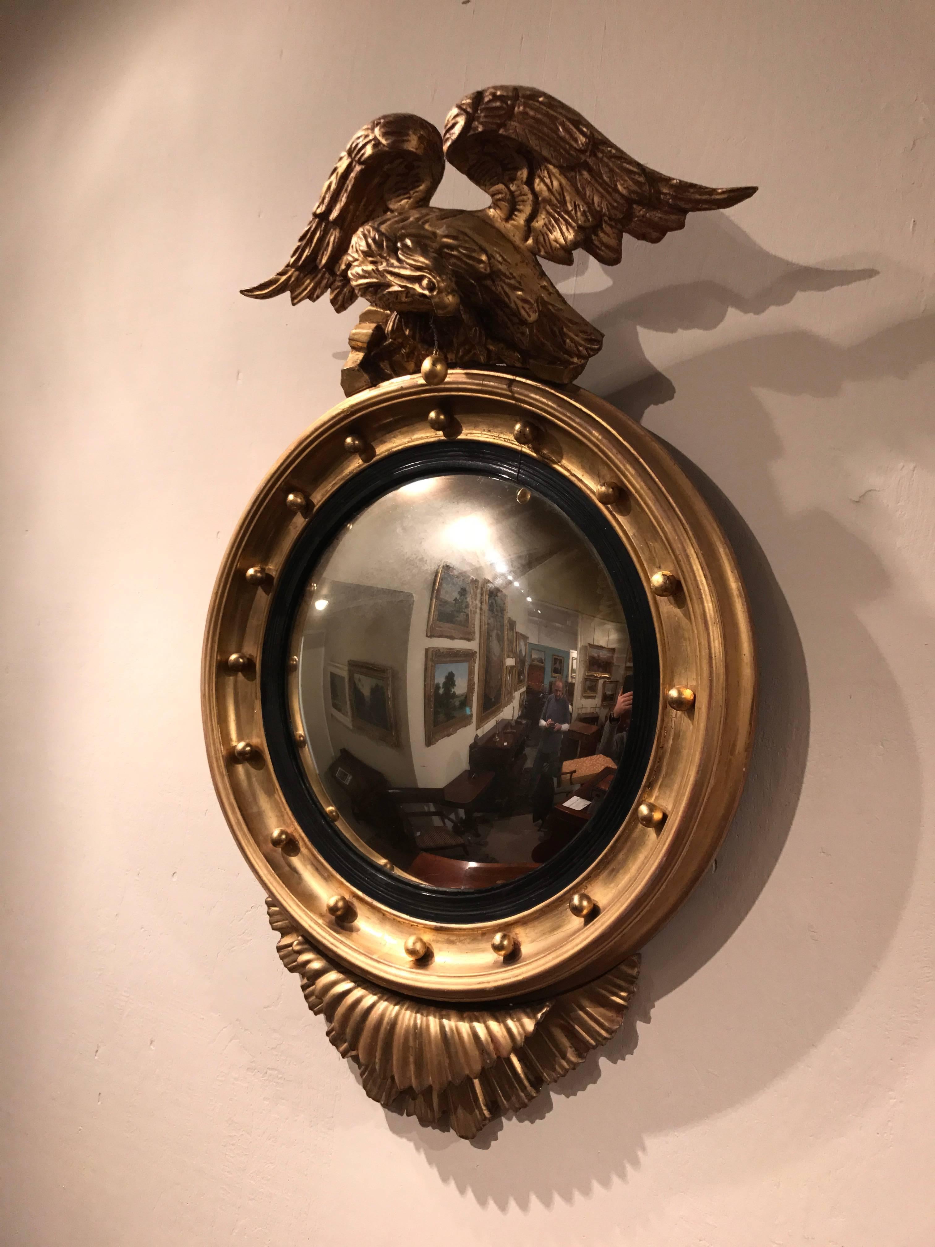 A handsome 19th century. Eagle crested gilt convex bullseye mirror with undulated foliate decoration to the lower section. Original condition.