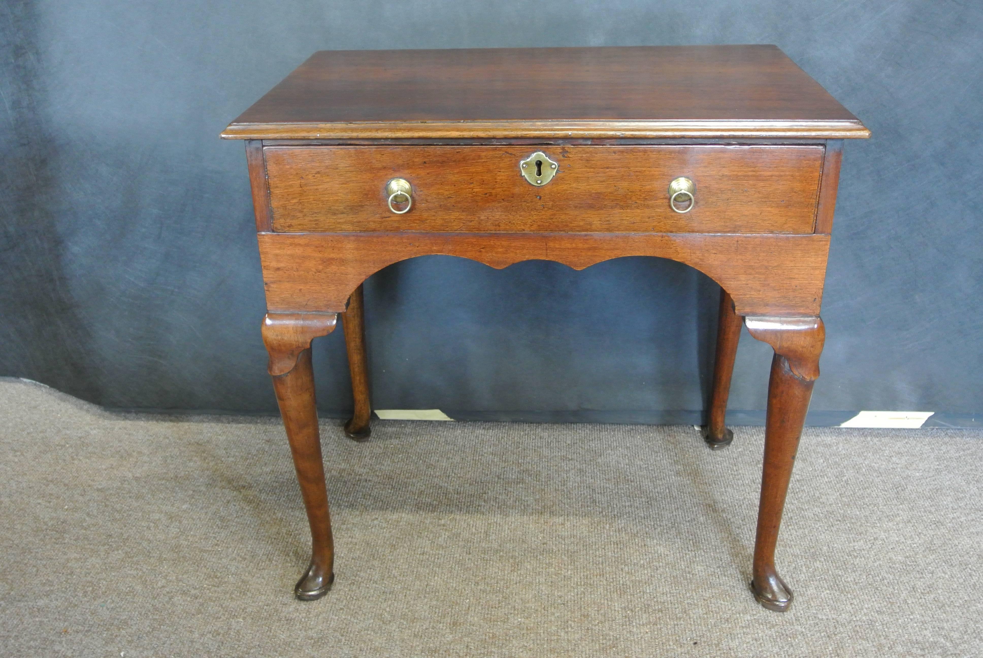 An elegant George II Virginia walnut lowboy with large centre draw with original paper lining and brassware. On four tapering cabriole legs with lappet carved knees ending on pointed toe pad feet.