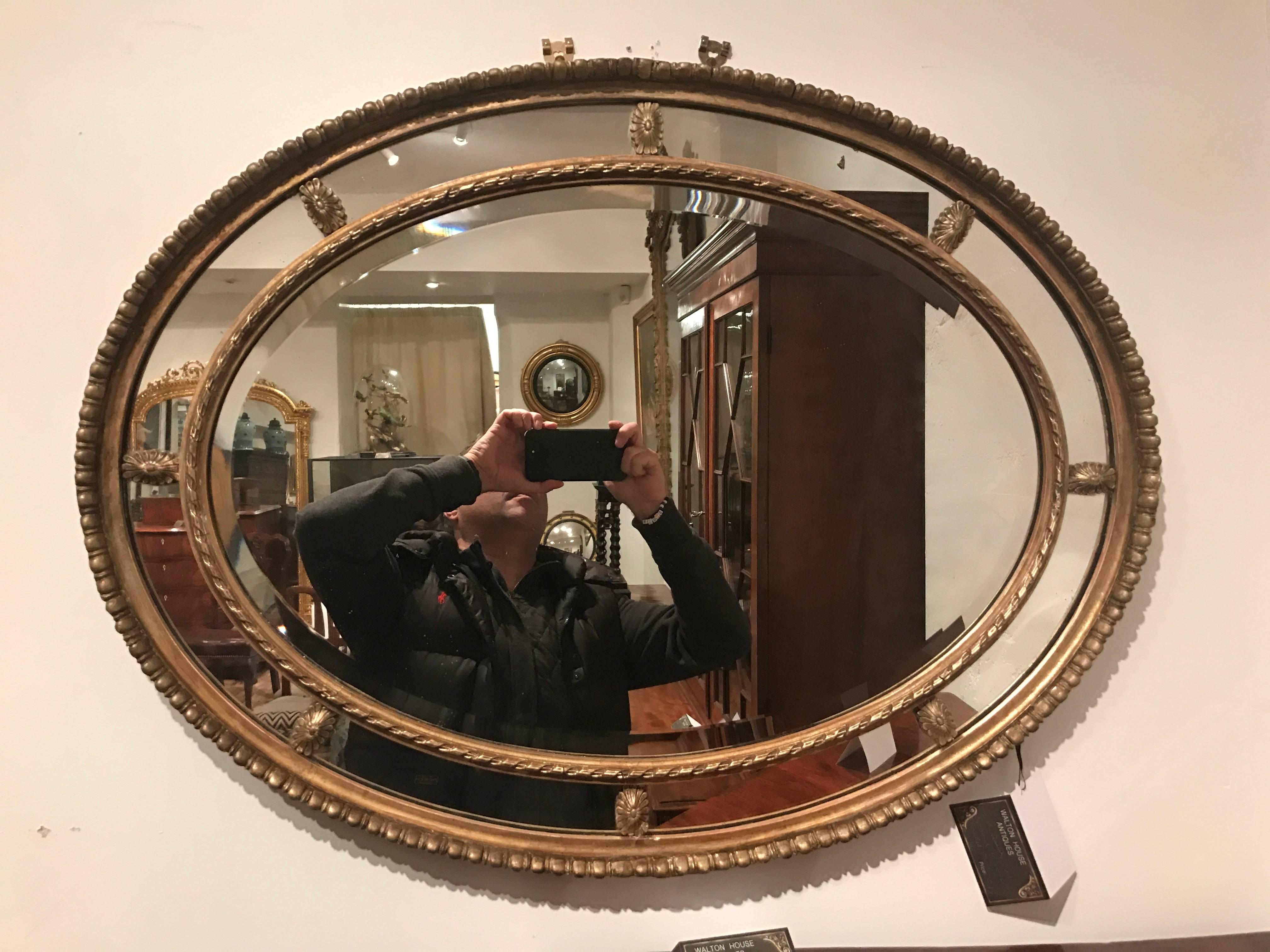 An early 20th century oval segmented Adam design gilt mirror with bevelled glass plates.
