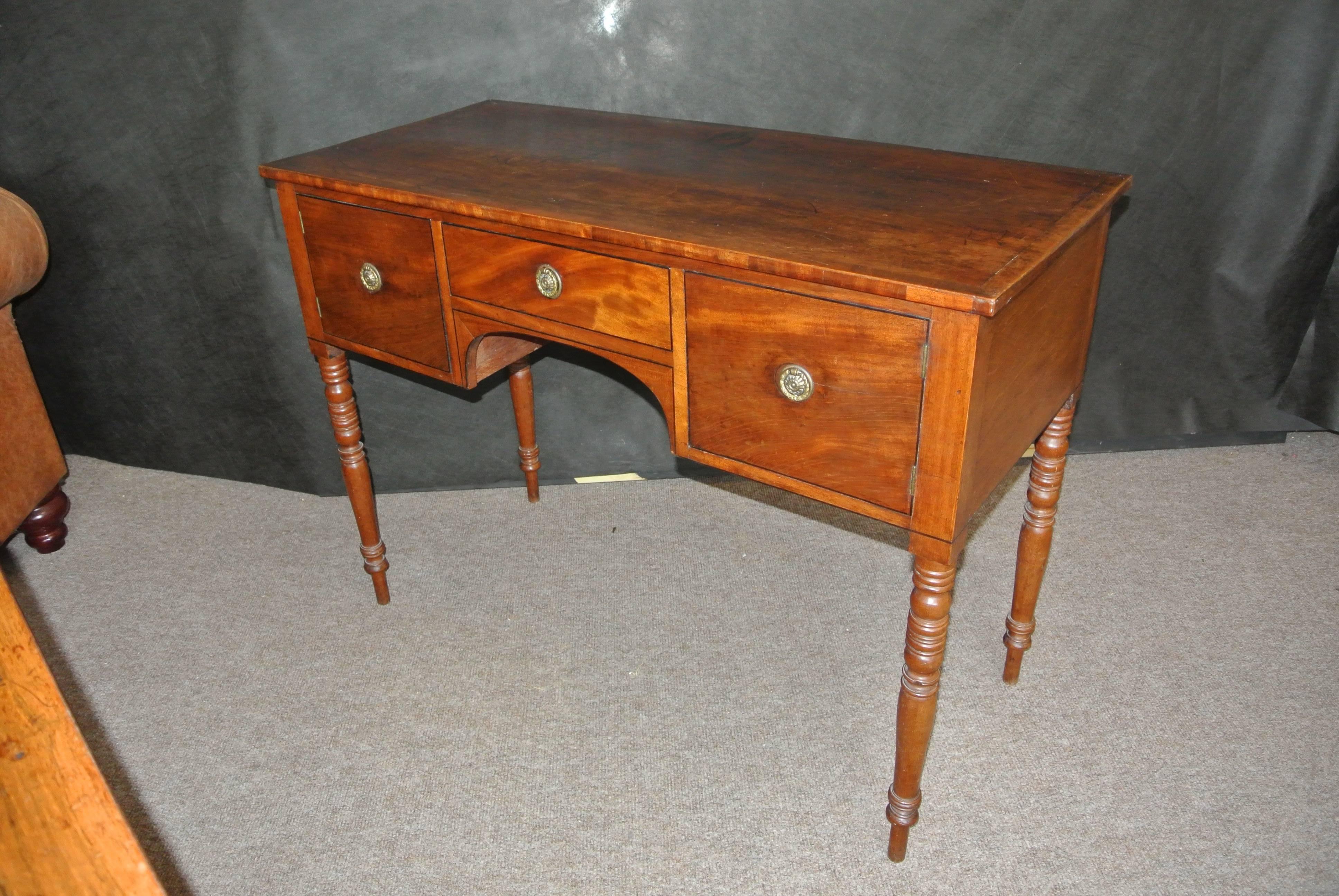 A beautifully figured 18th century George III mahogany kneehole side table with a large centre drawer and cabinets either side on four turned legs.