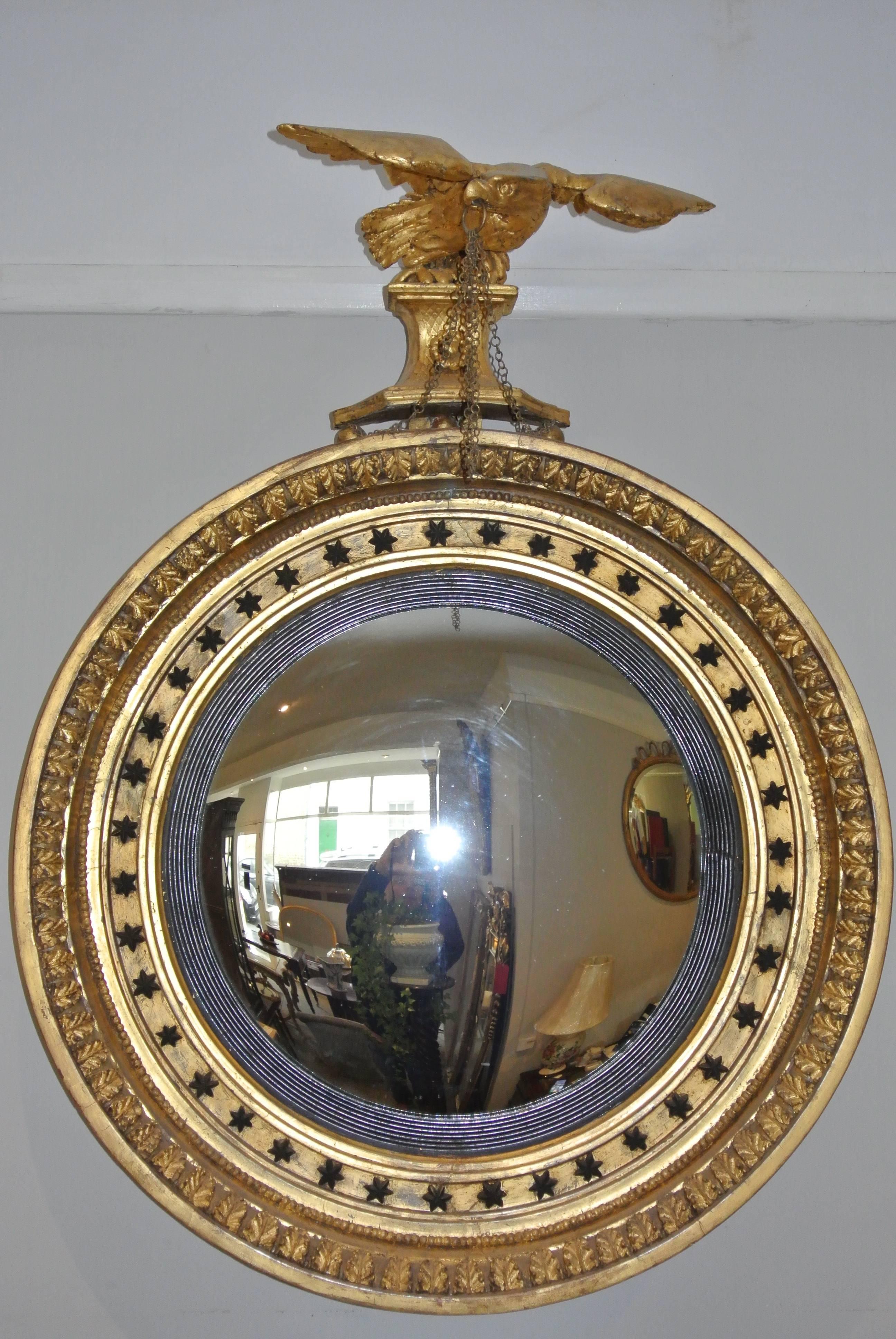 A fine quality Regency giltwood mirror of large proportions surmounted by a carved eagle and decorated with ebonised stars and acanthus leaves.