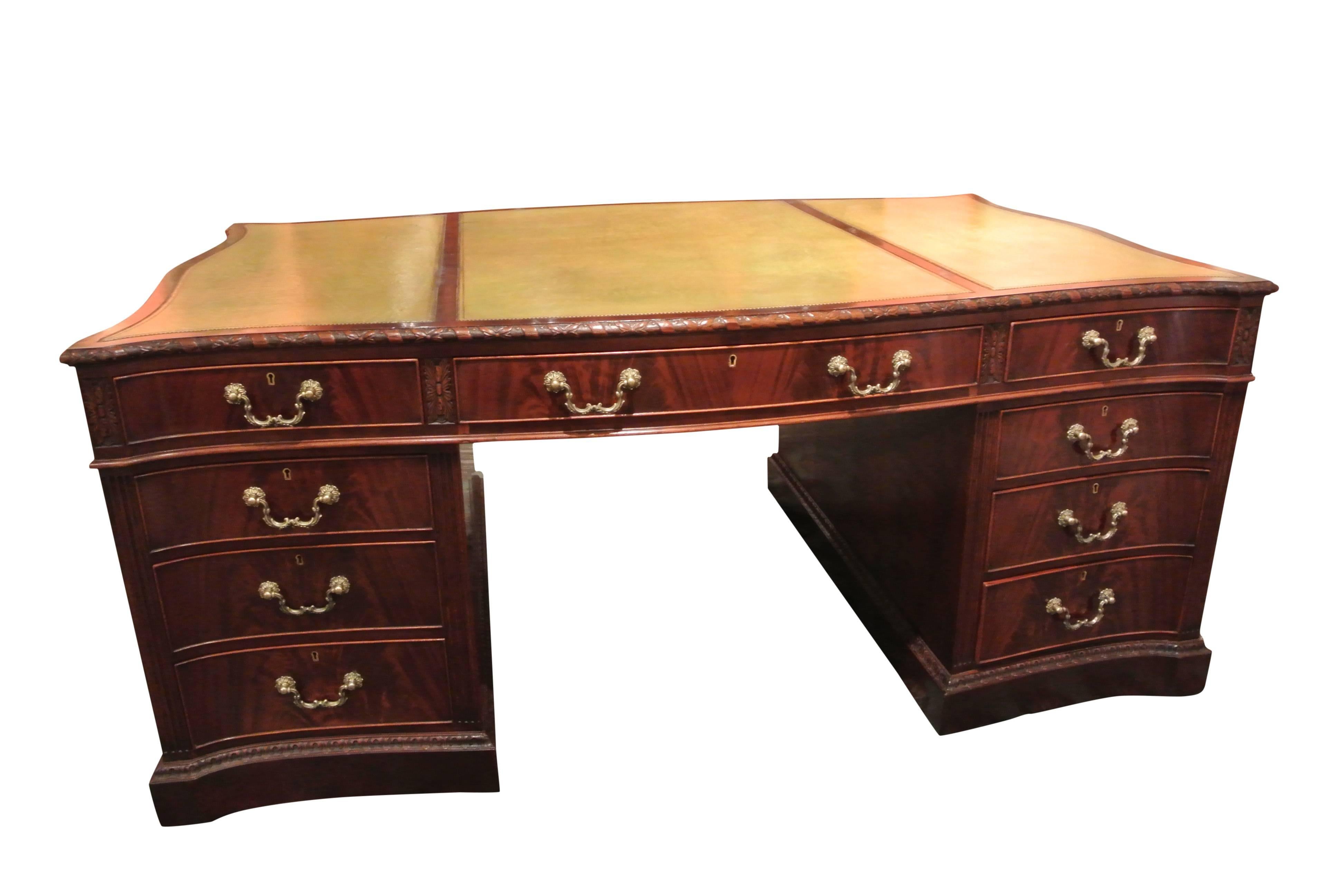 An impressive large mahogany serpentine shaped pedestal partners desk in the manner of Thomas Chippendale. The recently replaced triple panel light green leather inset top sits above an arrangement of nine drawers with original brass swan neck