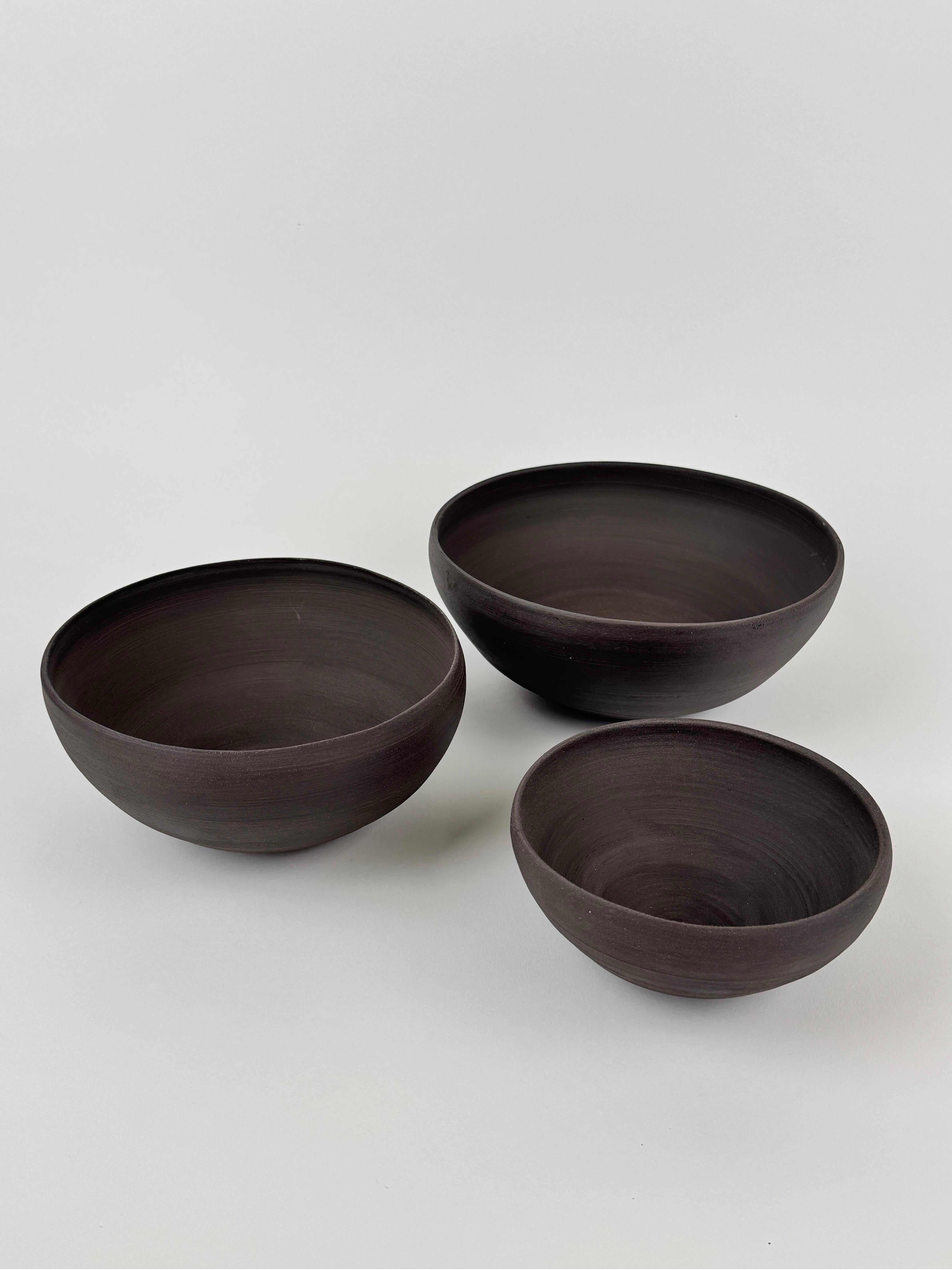 Este conjunto de cuencos nido de cerámica negra hechos a mano es un homenaje a la forma, la función y la belleza minimalista. Creados en un acabado mate con curvas suaves y orgánicas, cada cuenco encaja perfectamente con el siguiente, enfatizando el
