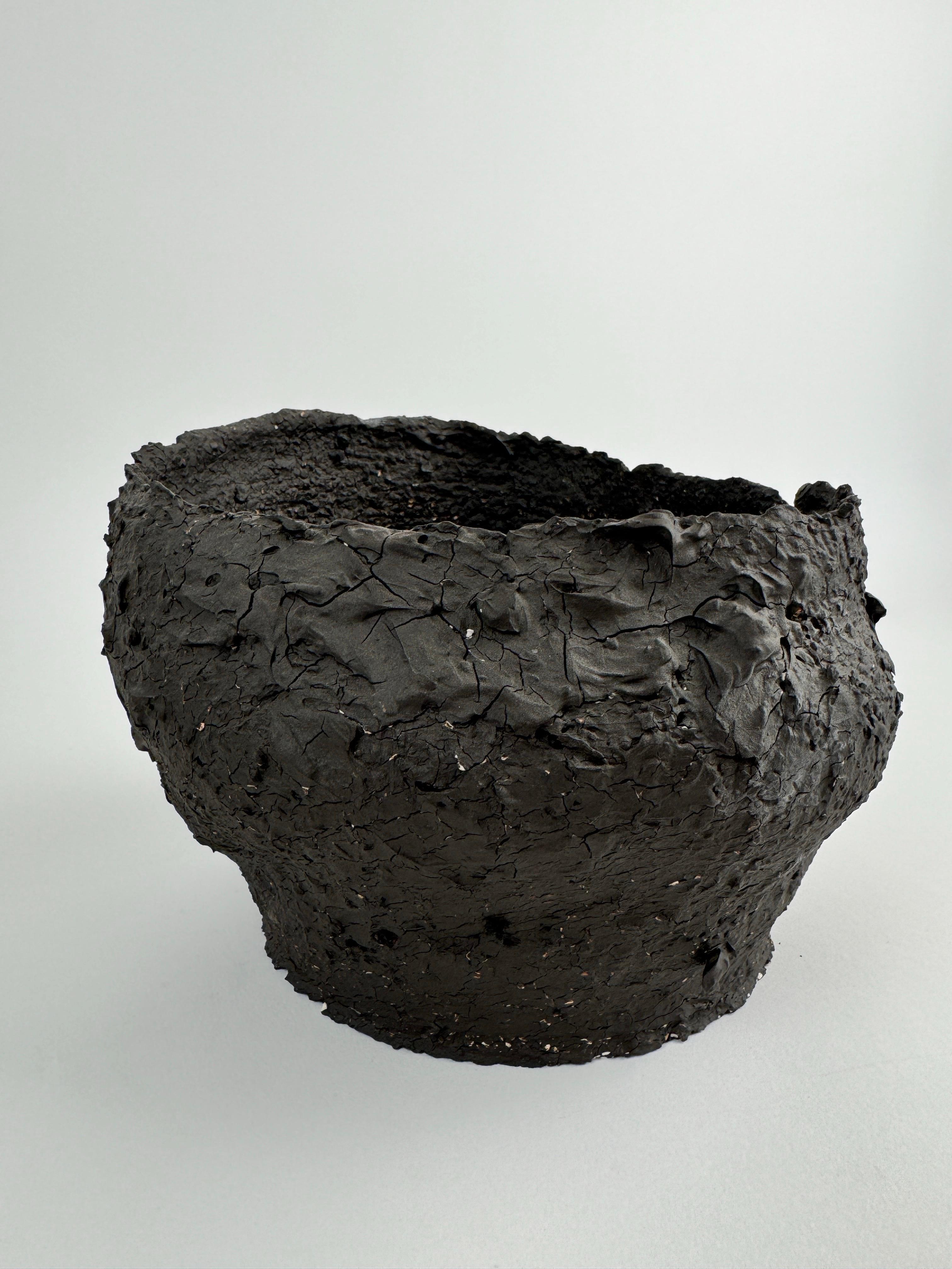 This one-of-a-kind sculptural ceramic object is hand-formed from deeply textured, high-fired stoneware. Its surface is raw and cracked, evoking the qualities of charred earth or weathered volcanic rock. The form is expressive yet minimal, making it