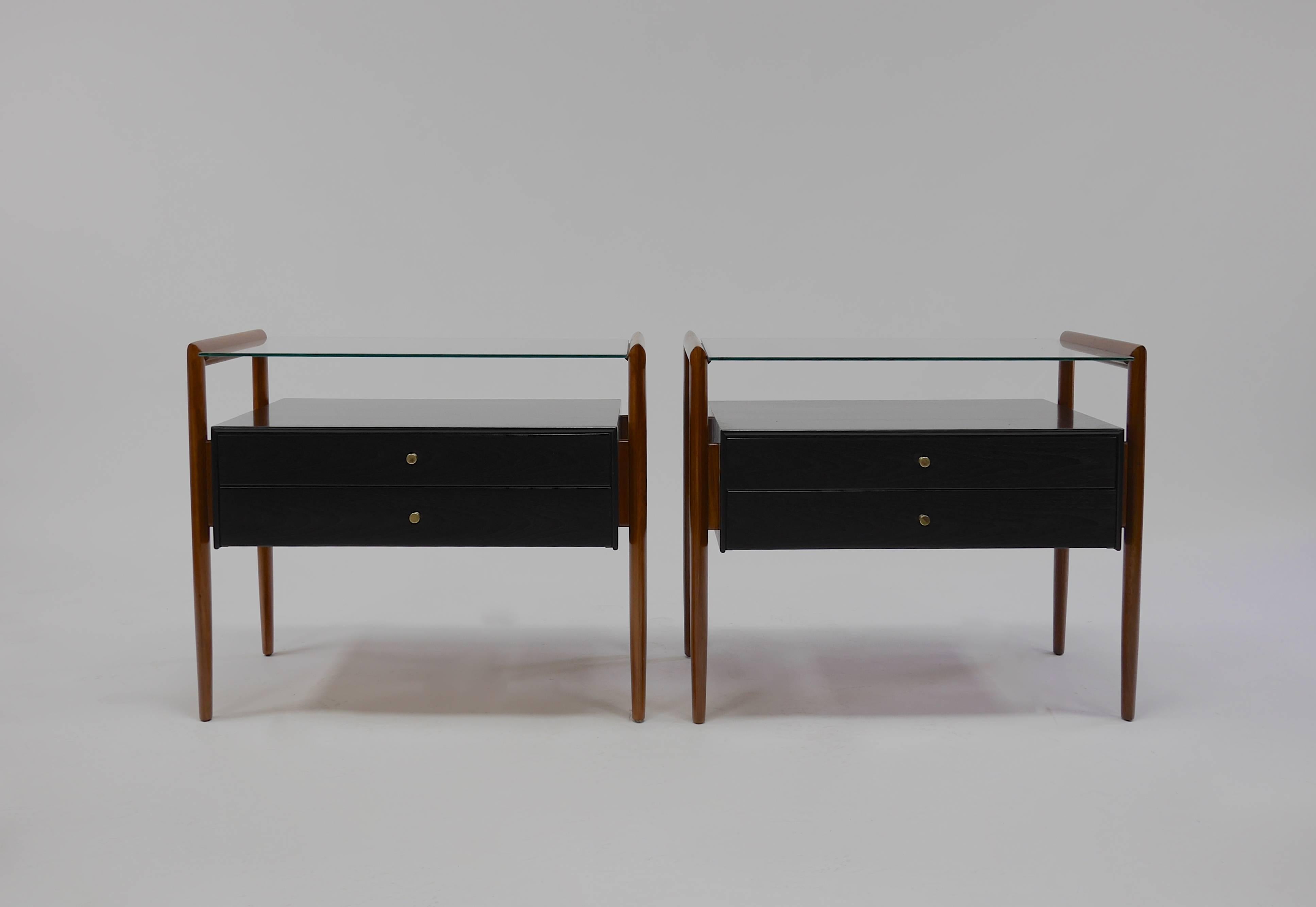Pair of Drexel Parallel group nightstands. Walnut and glass topped nightstands from Drexel's Parallel Group having two dovetailed drawers, suspended cabinets and ovoid legs. Machined brass pulls. Done in two-tone lacquer, the legs in natural and the