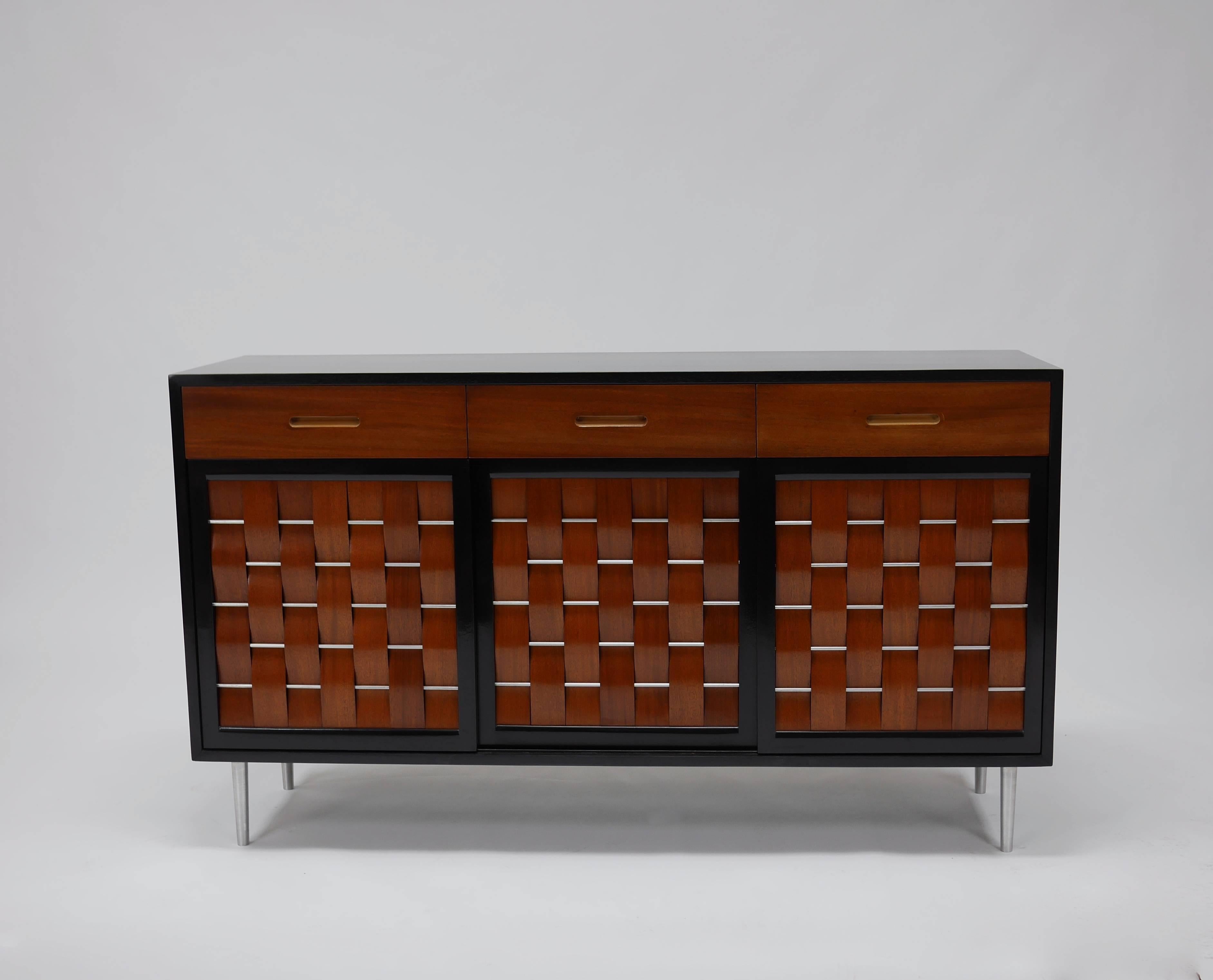 Edward Wormley for Dunbar. Model 5324 Credenza with two toned woven front doors and drawers, Features three top drawers with three sliding doors that conceal six drawers and two adjustable shelves. Aluminum accents and legs. Recent professional