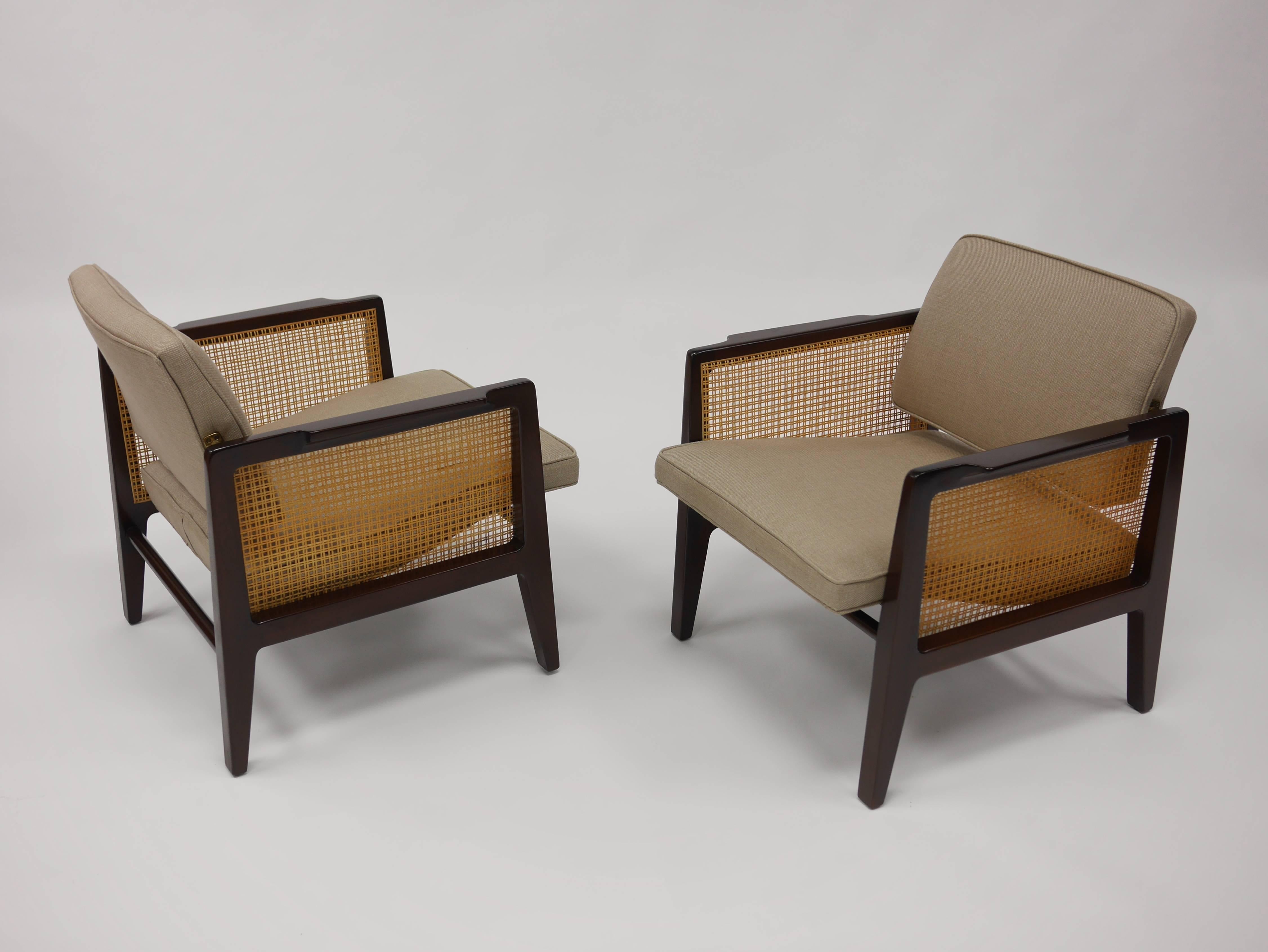Pair of lounge chairs model 5513 by Dunbar. Having sculpted mahogany frames, caned sides and brass hardware. The backs tilt to accommodate the angle of the sitter. These lounge chairs while smaller than typical, are very comfortable and as with all