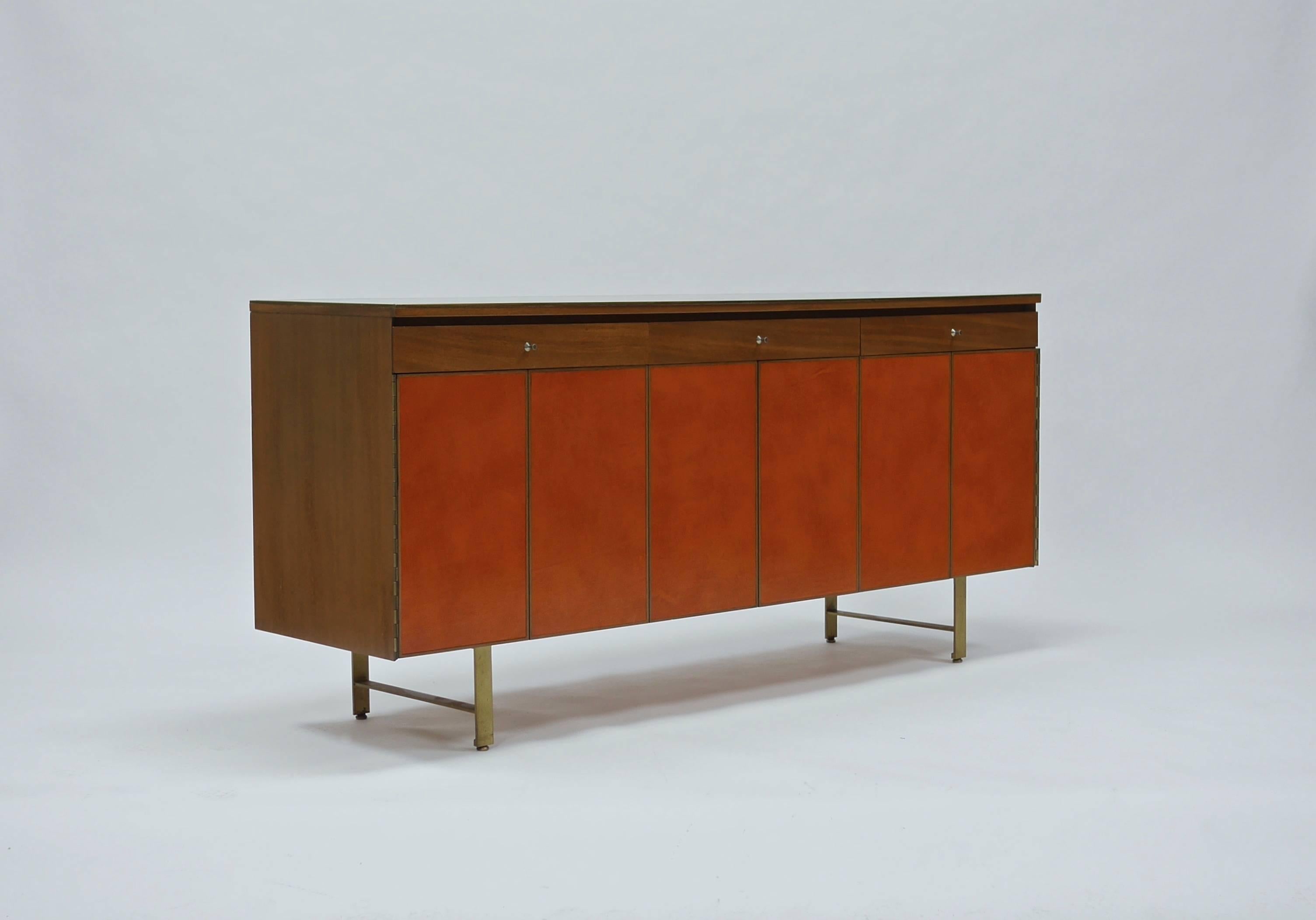 Rare and likely unique, Paul McCobb for Calvin Group walnut and leather front credenza with flat bar brass legs. Accordion trifold doors open to reveal adjustable shelving on the left and right. Upper drawers are leather lined . Excellent, original,