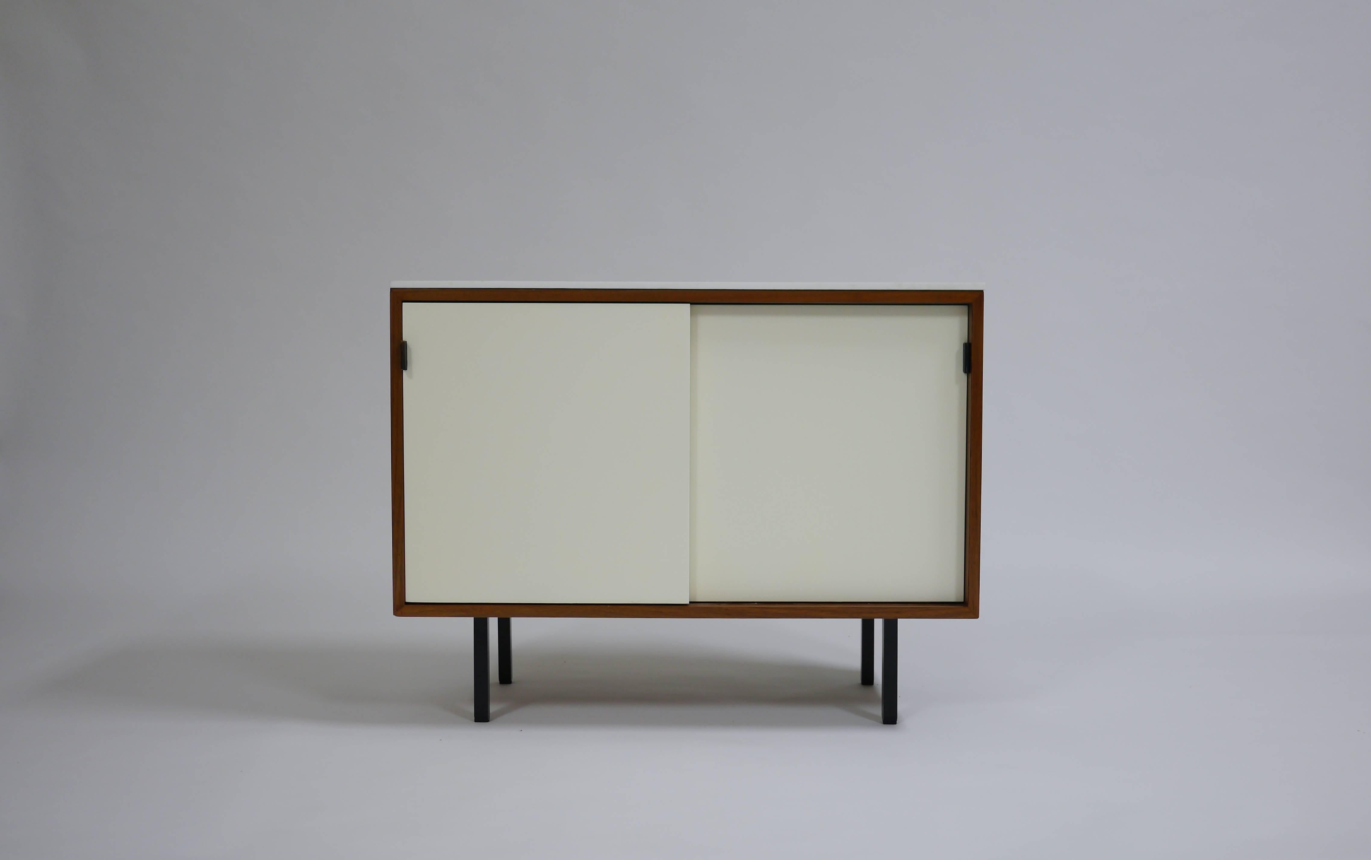 Pair of Knoll bar credenzas in white lacquer and walnut. The lower having a vitrolite, (white glass). Both have walnut cases, steel legs, oak lined interiors and walnut laminate tops.