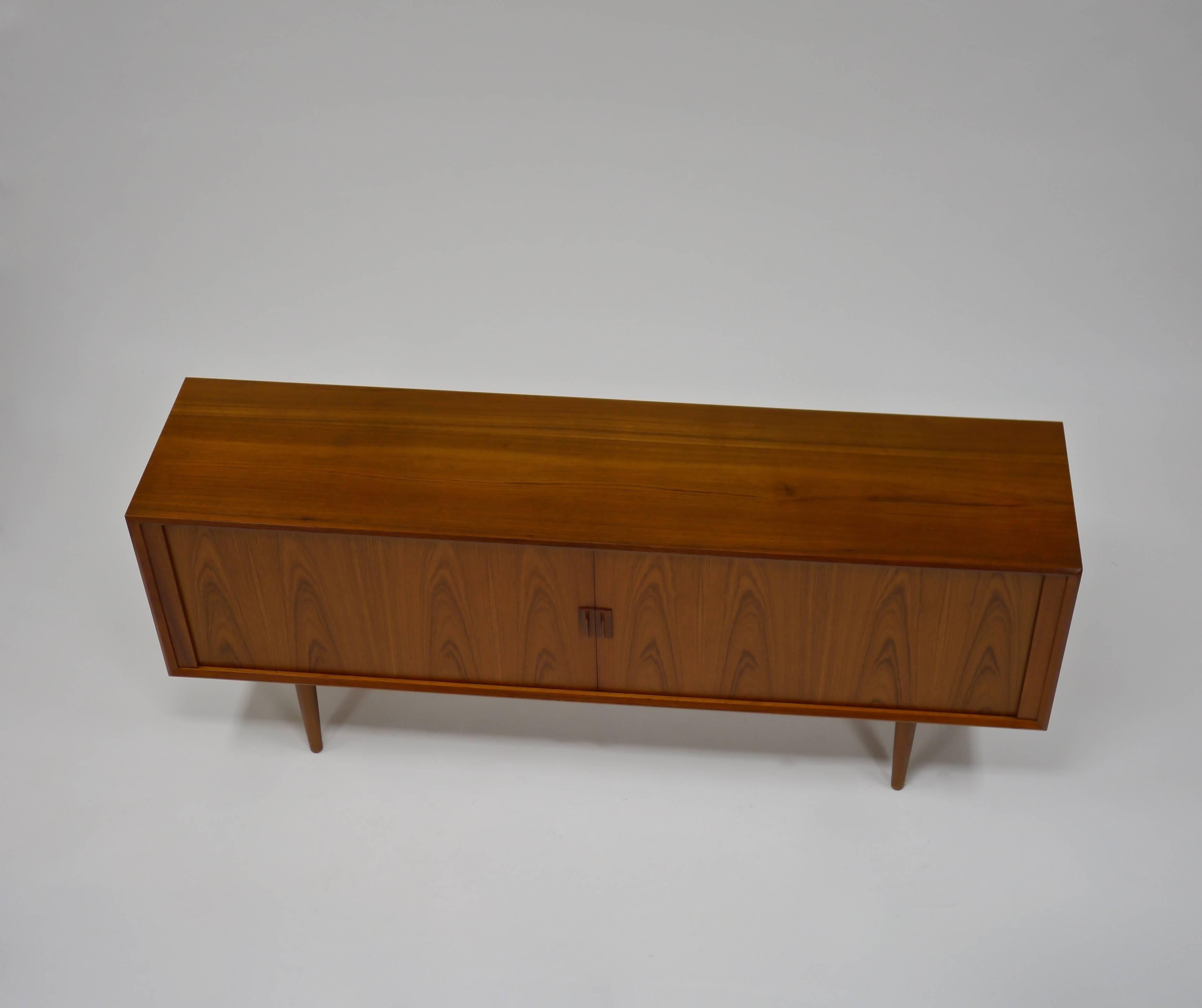 Credenza in teak by Svend A. Larsen for Faarup Mobelfabrik. Having a finished back, bookmatched tambour doors, four drawers and three shelves.