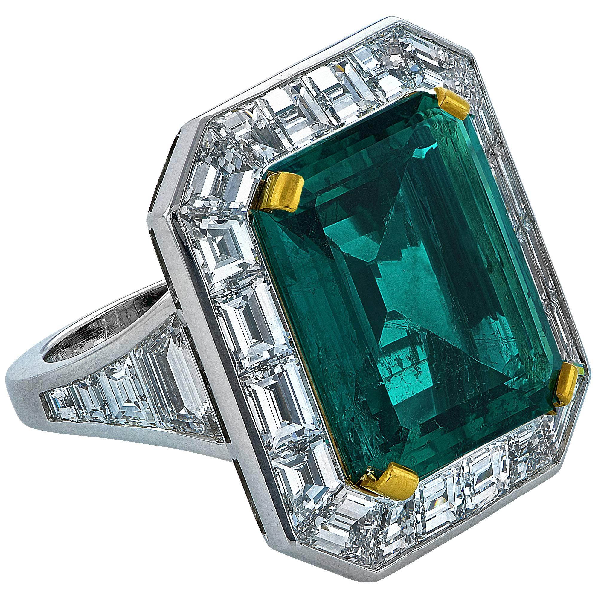 Custom handmade platinum ring starring a 10.10ct deep, vibrant green emerald with a Columbia origin, accompanied by an AGL report stating minor traditional. This rare emerald is surrounded by 16 custom wide cut baguettes weighing 5.55cts D-E color