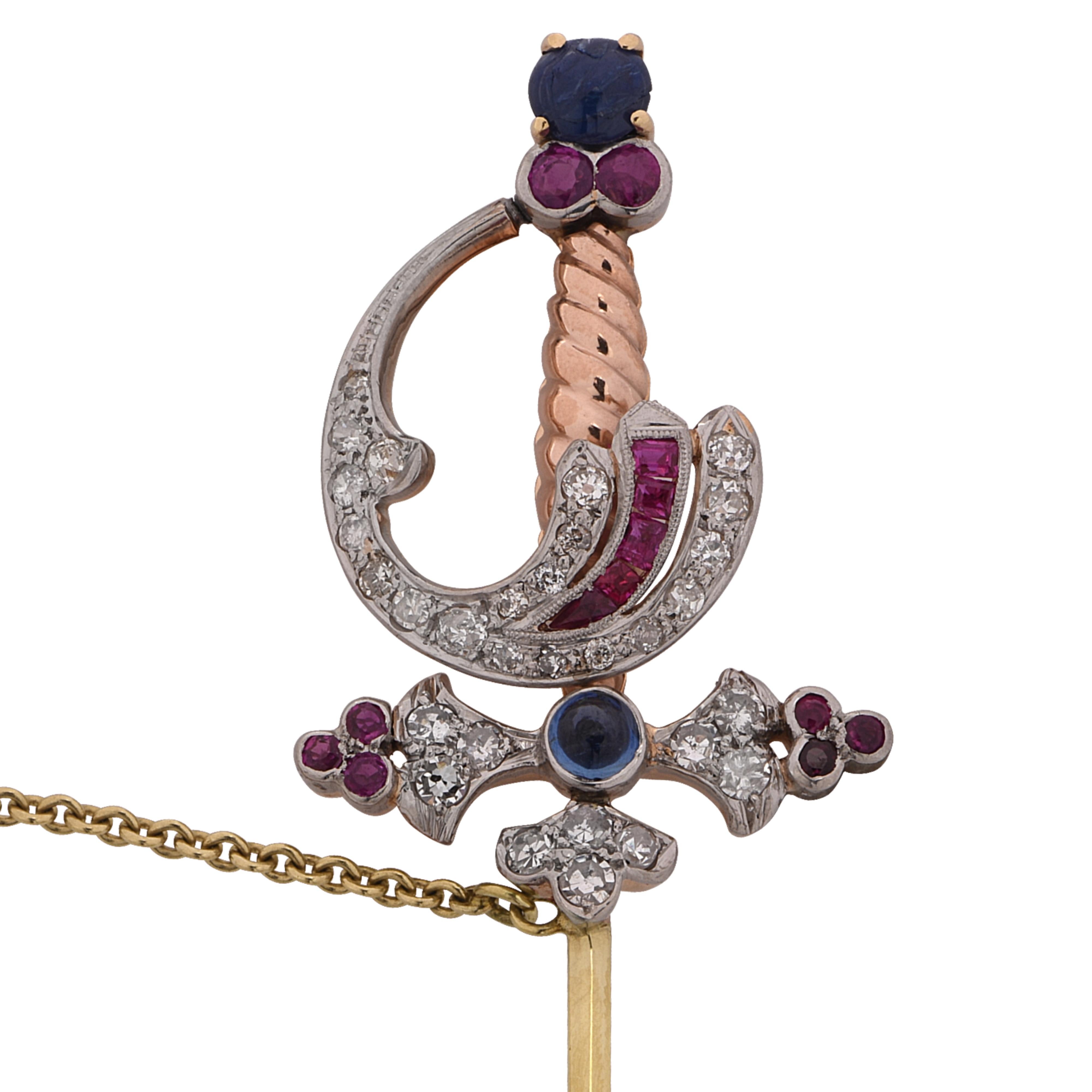 Ornate Victorian jabot brooch pin crafted in yellow, white and rose gold, featuring a sabot sword detailed with 42 European and single cut diamonds weighing approximately 1 carat, and 15 rubies and 2 sapphires weighing approximately .80 carats. This