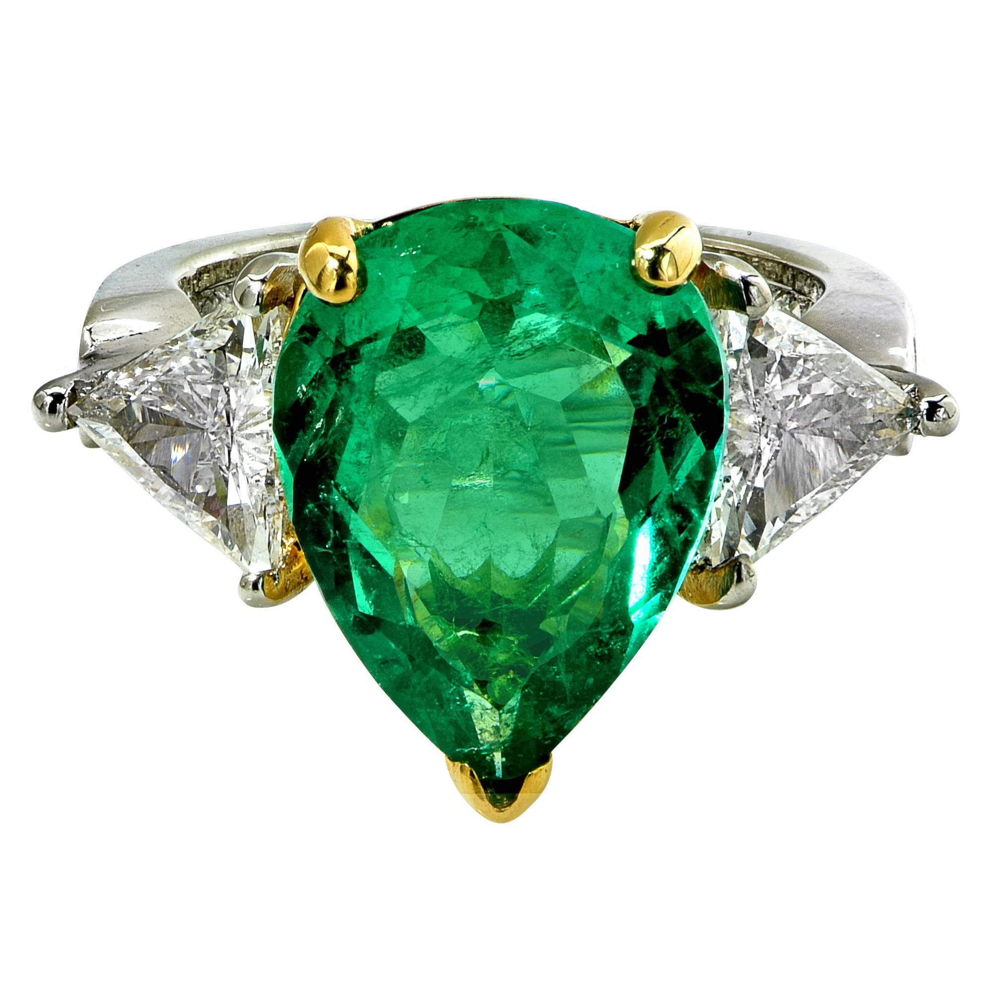Platinum lady's ring featuring a pear shape emerald weighing 4.34cts flanked by two trilliant cut diamonds with an estimated total weight of 1.80cts, G-H color, VS clarity, accented by 48 princess and round cut diamonds weighing approximately