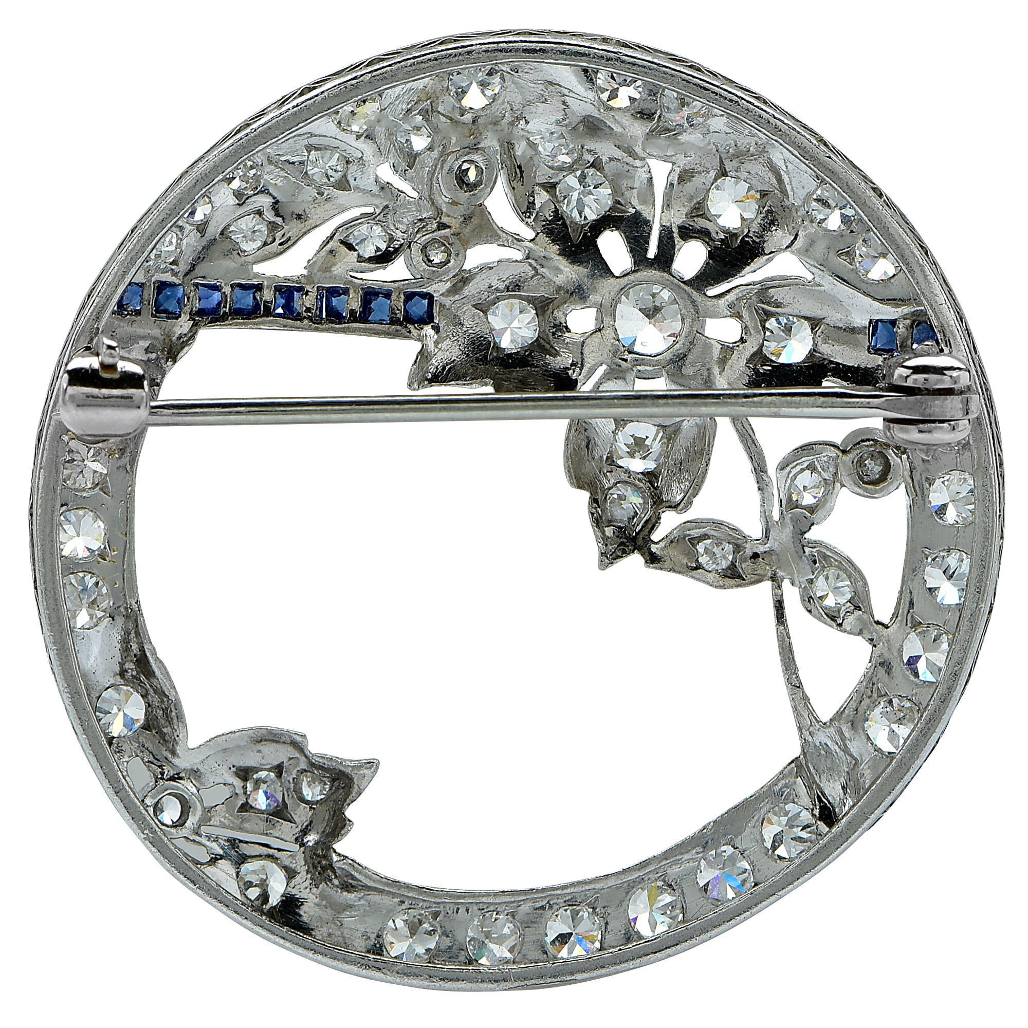 Platinum vintage brooch featuring approximately 2cts of old European cut diamonds, G color, VS clarity, accented by .11cts of blue sapphires.

Metal weight: 8.08 grams

This diamond brooch is accompanied by a retail appraisal performed by a