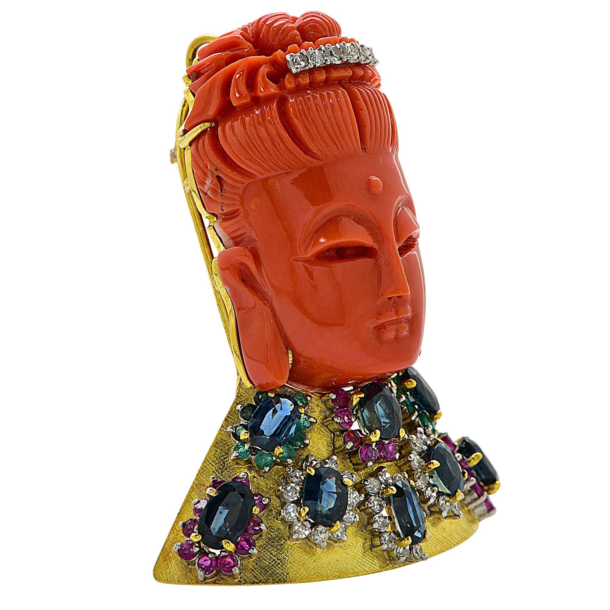 18k yellow gold brooch featuring a carved coral happy Buddha, accented by 9 oval cut sapphires weighing approximately 6cts total, 39 single cut diamonds weighing .60cts, 28 sapphires weighing .50cts total and 18 emeralds weighing .20cts