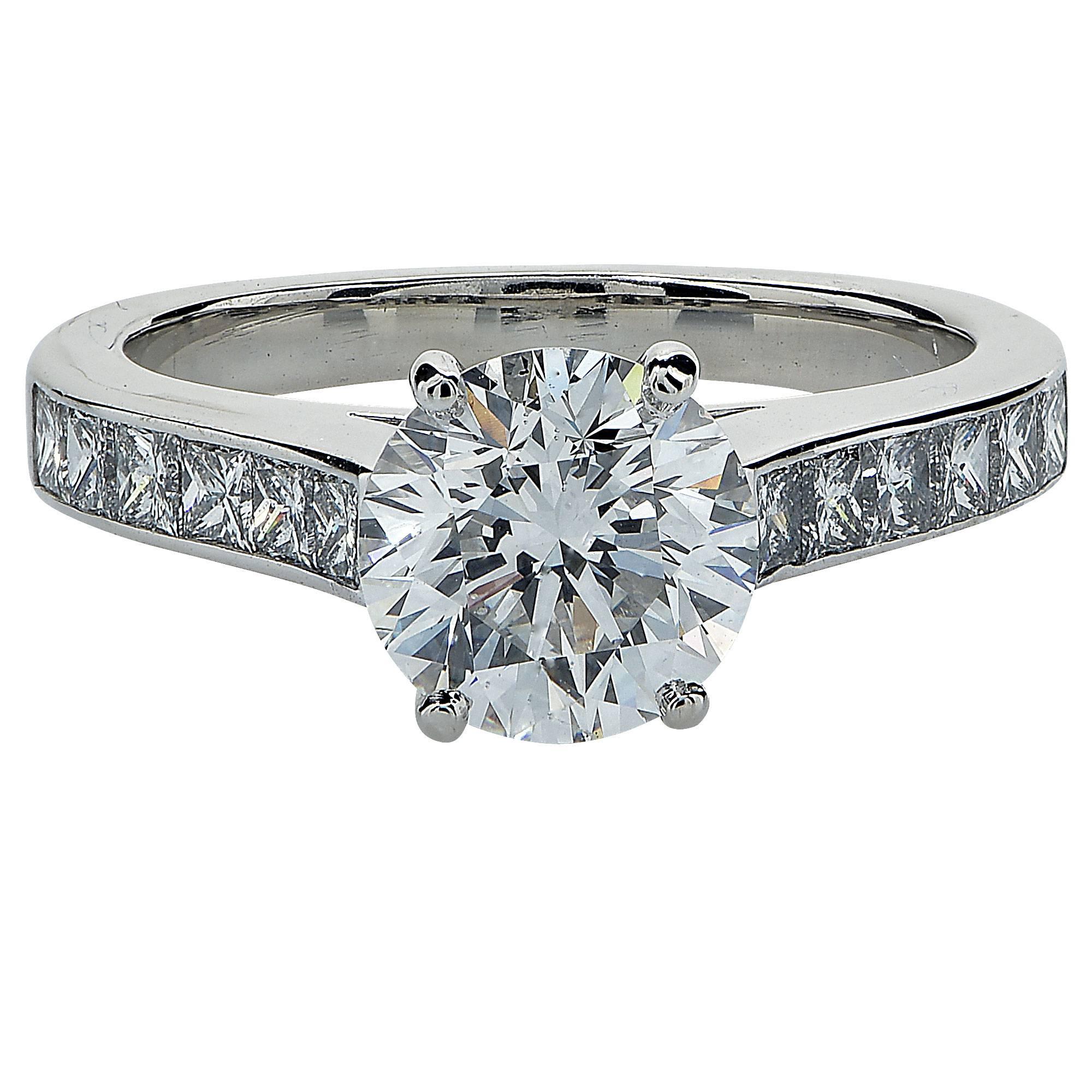 18k white gold ring featuring a GIA graded 1.55ct F color, SI1 clarity round brilliant cut diamond. Accented by 12 princess cut diamonds weighing approximately .60cts total G color, VS clarity. 
