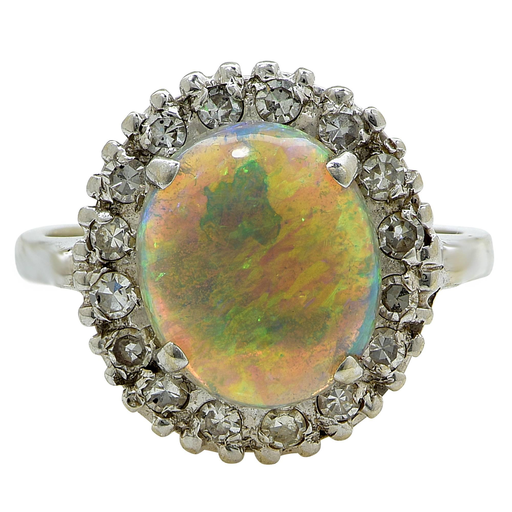 White gold ring containing a cabochon opal measuring 10.92mm by 9.24mm by 3.89mm surrounded by 16 single cut diamonds weighing approximately .25cts.

The ring is a size 5 and can be sized up or down.
It is stamped and tested as 14k gold.
The