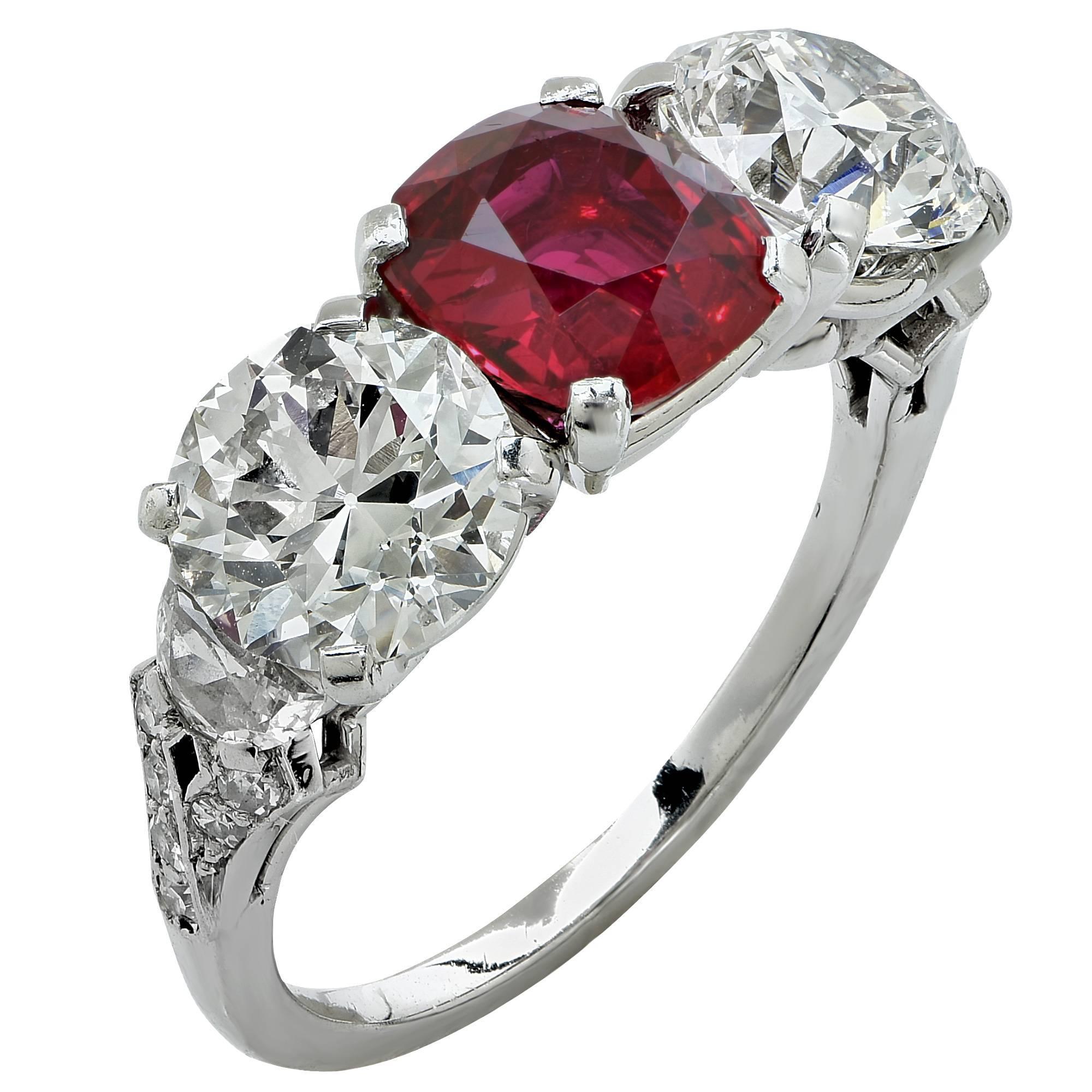 Platinum Art Deco ring contaning a vibrant red ruby cushion cut weighing approximately 2cts flanked by 2 European cut diamonds weighing approximately 2.60cts G-H color and VS clarity accented by 2 half moon cut diamonds approximately .30ct and 12