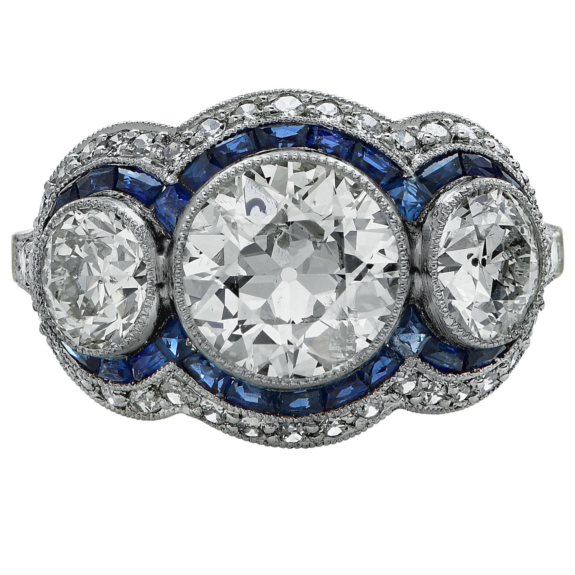 Platinum handmade ring featuring a European cut diamond weighing approximately 1.15cts H color SI clarity flanked by 2 European cut diamonds weighing approximately 1.40cts total, H color VS clarity accented by approximately .45cts of European cut