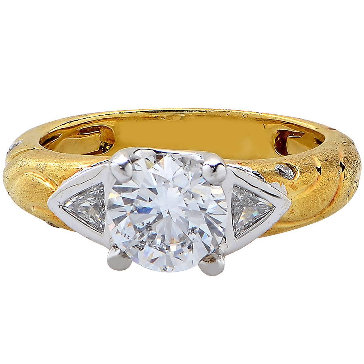 18 yellow gold ring featuring a GIA graded 1.50ct D color I1 clarity round brilliant cut diamond flanked by two trilliant cut diamonds and 12 round brilliant cut diamonds weighing .36cts.

The ring is a size 6 and can be sized up or down.
It is