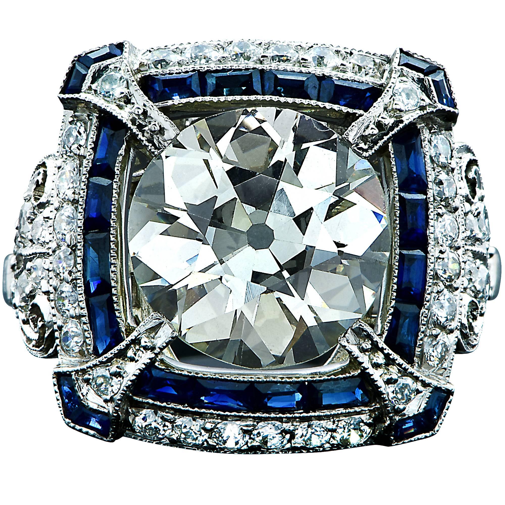 Platinum ring containing a 3.80ct European cut diamond M color and VS clarity surrounded by 24 custom cut sapphires weighing approximately .75cts and 52 European cut diamonds weighing approximately 1cts.

The ring is a size 6.5 and can be sized up