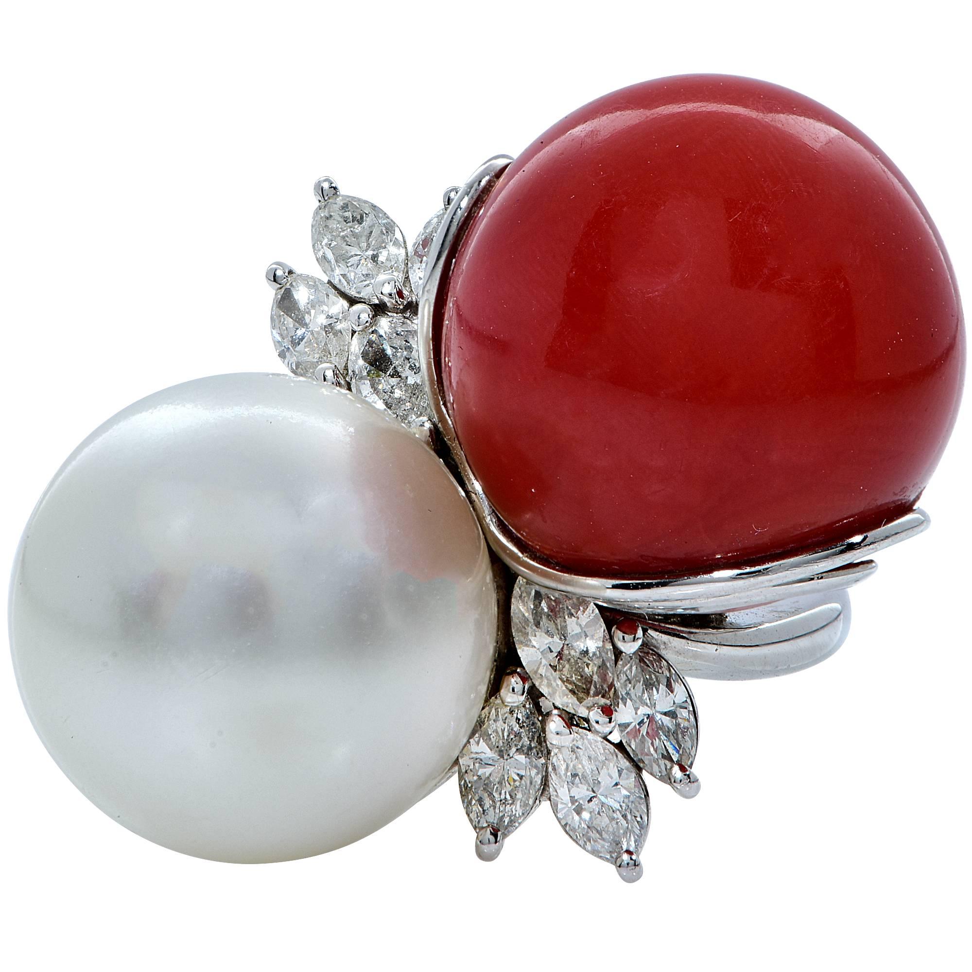 Platinum ring containing circular piece of vibrant red coral measuring 17.1mm flanked by an icy white South Sea Pearl measuring 16.30mm accented by 8 marquise cut diamonds weighing approximately 1.60ct I-J color and SI clarity. This ring weighs