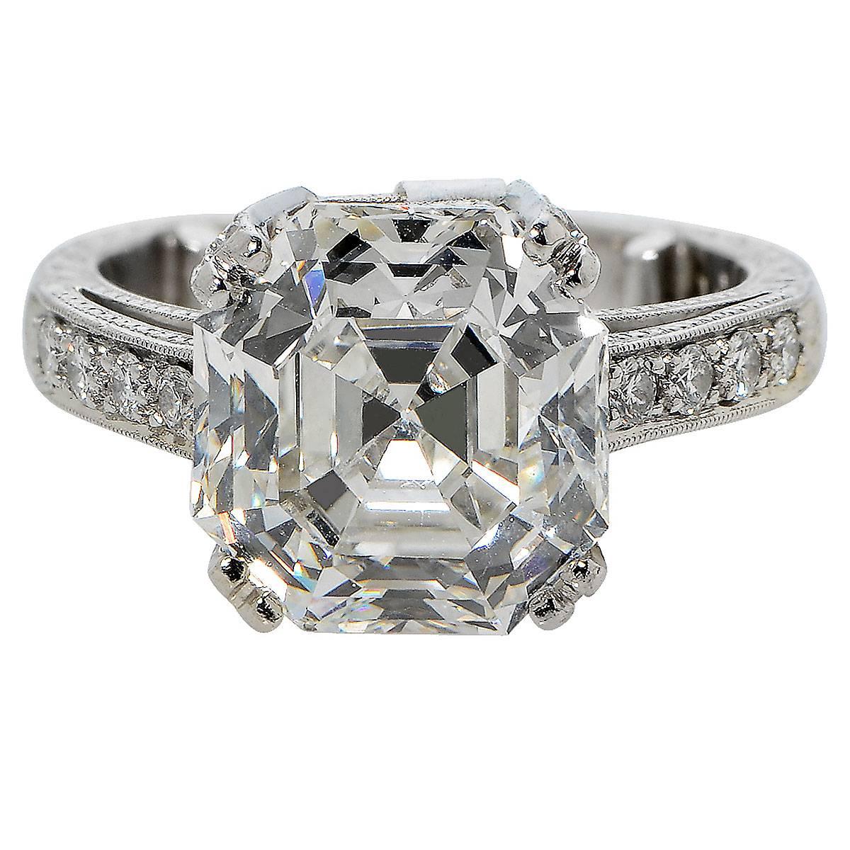 This stunning platinum ring features a 6.32ct square emerald / asscher cut diamond,  H color, VS1 clarity, and is accompanied by a GIA report. The center diamond is accented by .85ct of round brilliant cut diamonds, G color, VS clarity. Its total