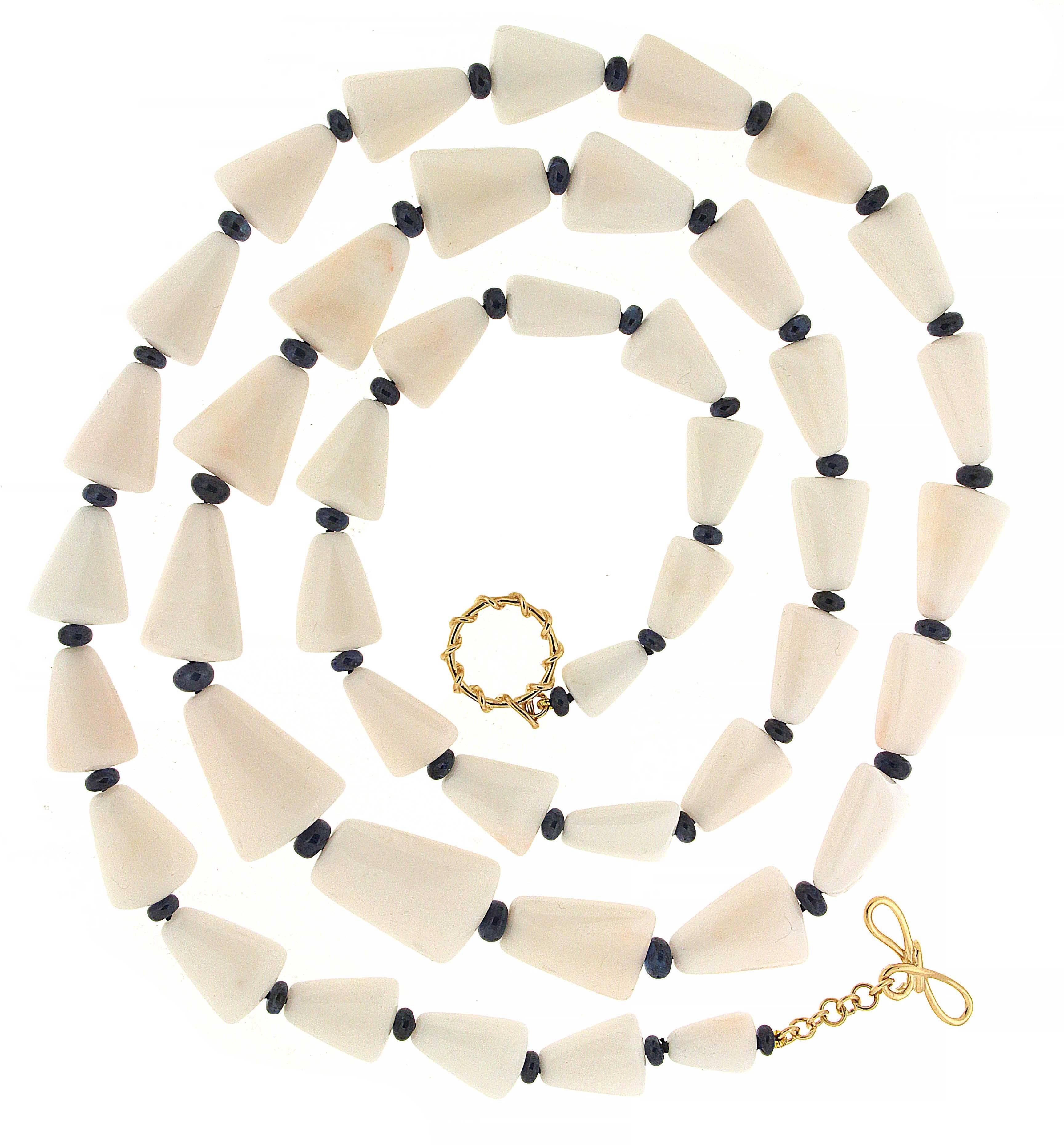 One of the most iconic designs, this necklace is made in 18kt yellow gold, it features graduating size white triangular coral with blue sapphire rondelles, and is finished with a ring and toggle clasp. 