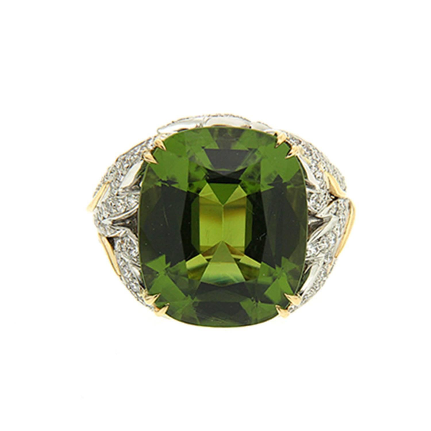 This ring features a Cushion Peridot 18.39ct with diamond pave leafs on the side. The ring is finished in 18kt yellow gold.