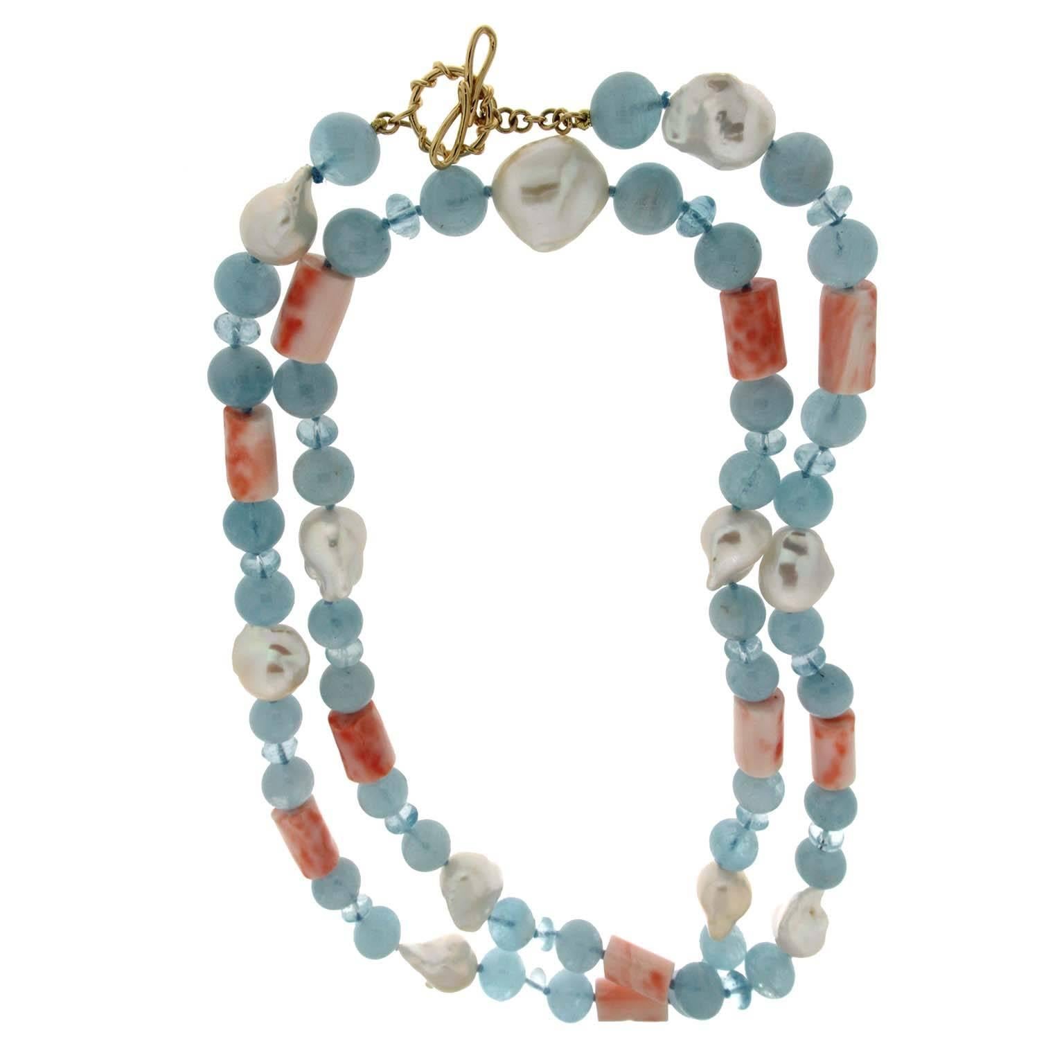 This necklace features a strand of coral tubes, aquamarine balls, and fresh water baroque pearls, it is complete with an 18kt yellow gold ring and toggle clasp. 