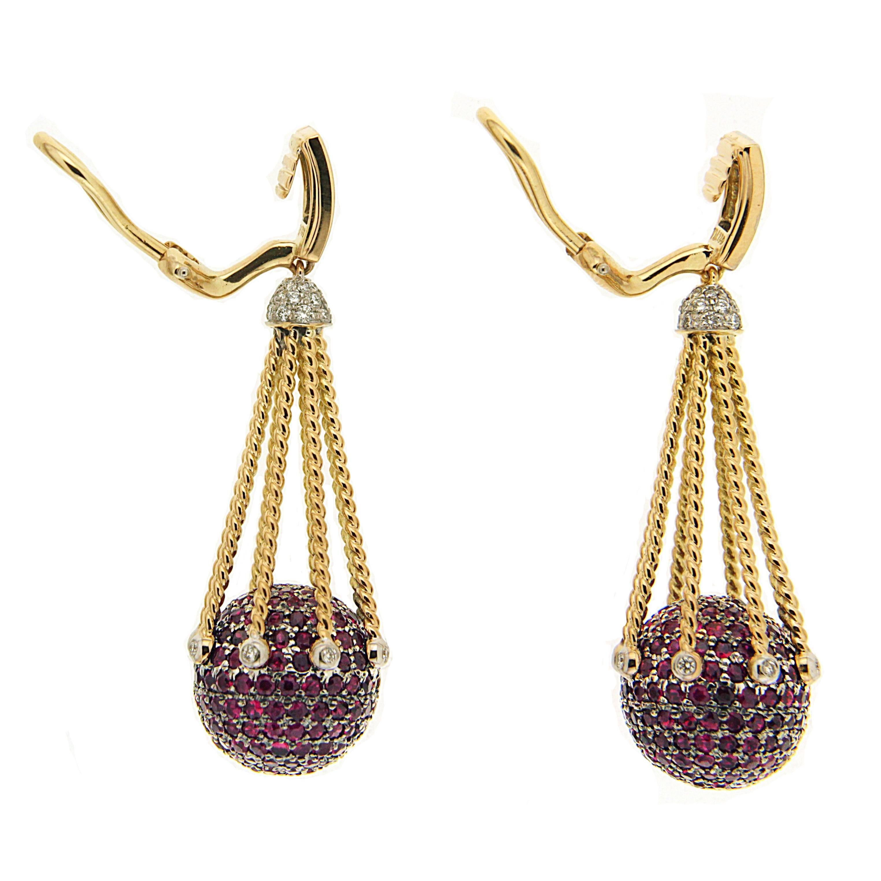 One of the most unique jewelry designs, this elegant pair of earrings features Ruby pave balls with diamond caps on the top connected by multiple gold twisted ropes and ended with bezel set diamond accents. The earring is finished in 18kt Yellow