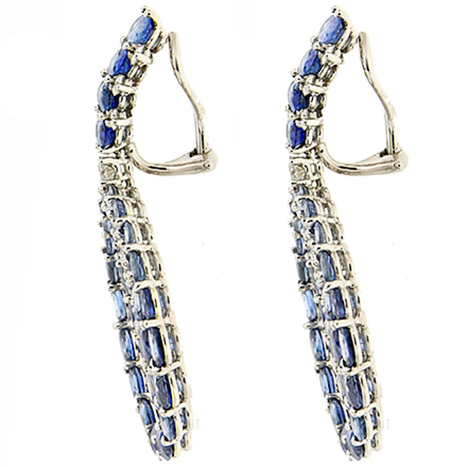 This amazing pair of earrings features beautiful oval blue sapphires in different sizes and shades with diamond accents. The earrings are finished in platinum with clip backs.