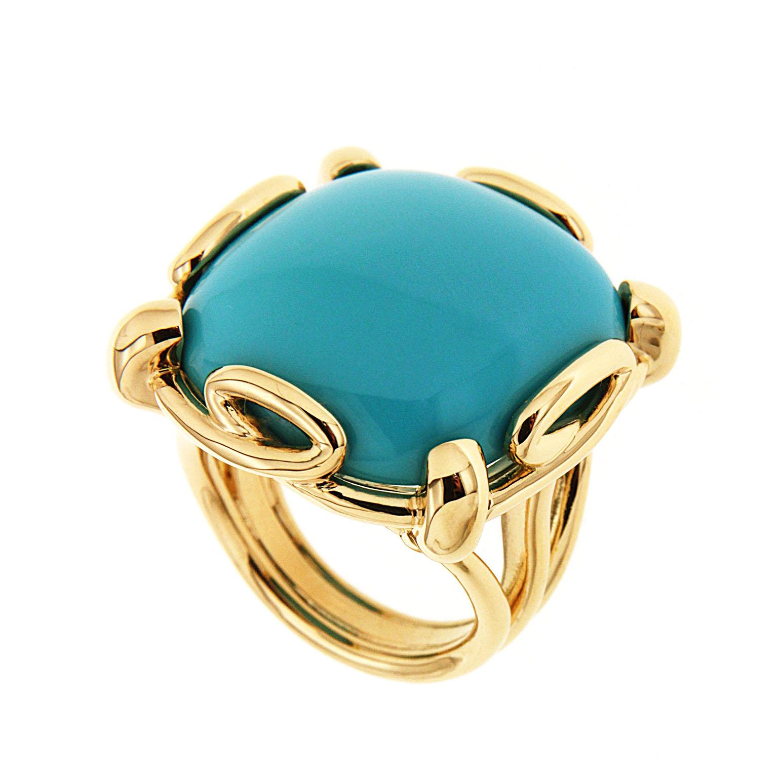 This unique ring features a cushion Turquoise cabochon center with loop design motifs. The ring is completed in 18kt yellow gold.