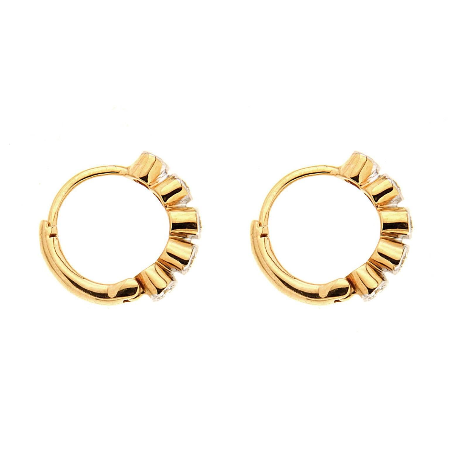 These delicate hoop earrings are made in 18kt yellow gold they feature 0.24 carat total weight of bezel set round brilliant diamonds.