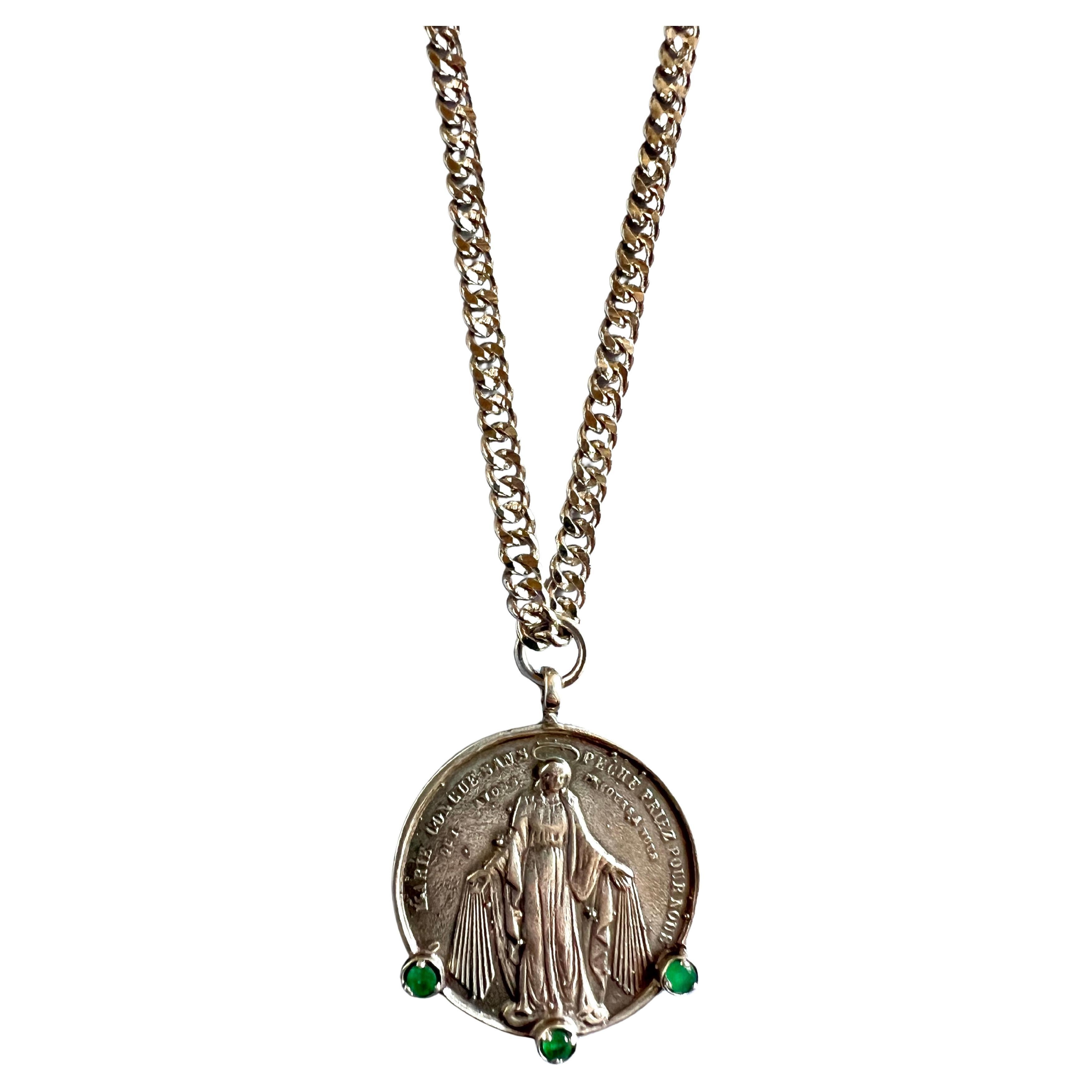 Medal Chain Necklace with 3 Emeralds Virgin Mary Coin Silver
Chain is Platinum plated Brass

Designer: J DAUPHIN 

This medal necklace is adorned with three large emeralds, which are celebrated for their lush green color, symbolizing renewal,