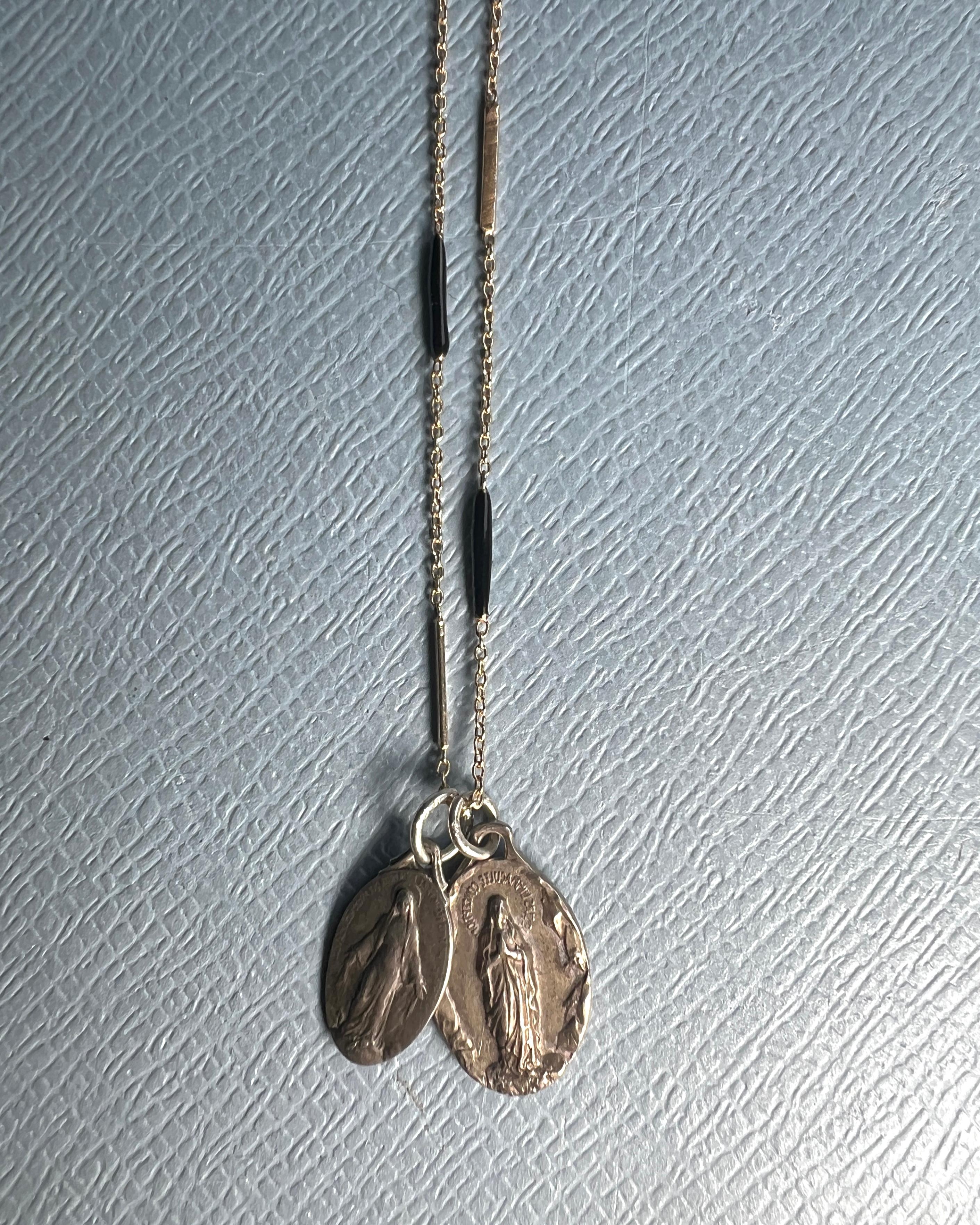 Medaglia della Vergine Maria Vintage  Collana con ciondolo in smalto nero

Progettista: J Dauphin

Questa collana simbolica di J DAUPHIN presenta due mini medaglie francesi vintage della Vergine Maria appese a una catena nera smaltata a mano di 28
